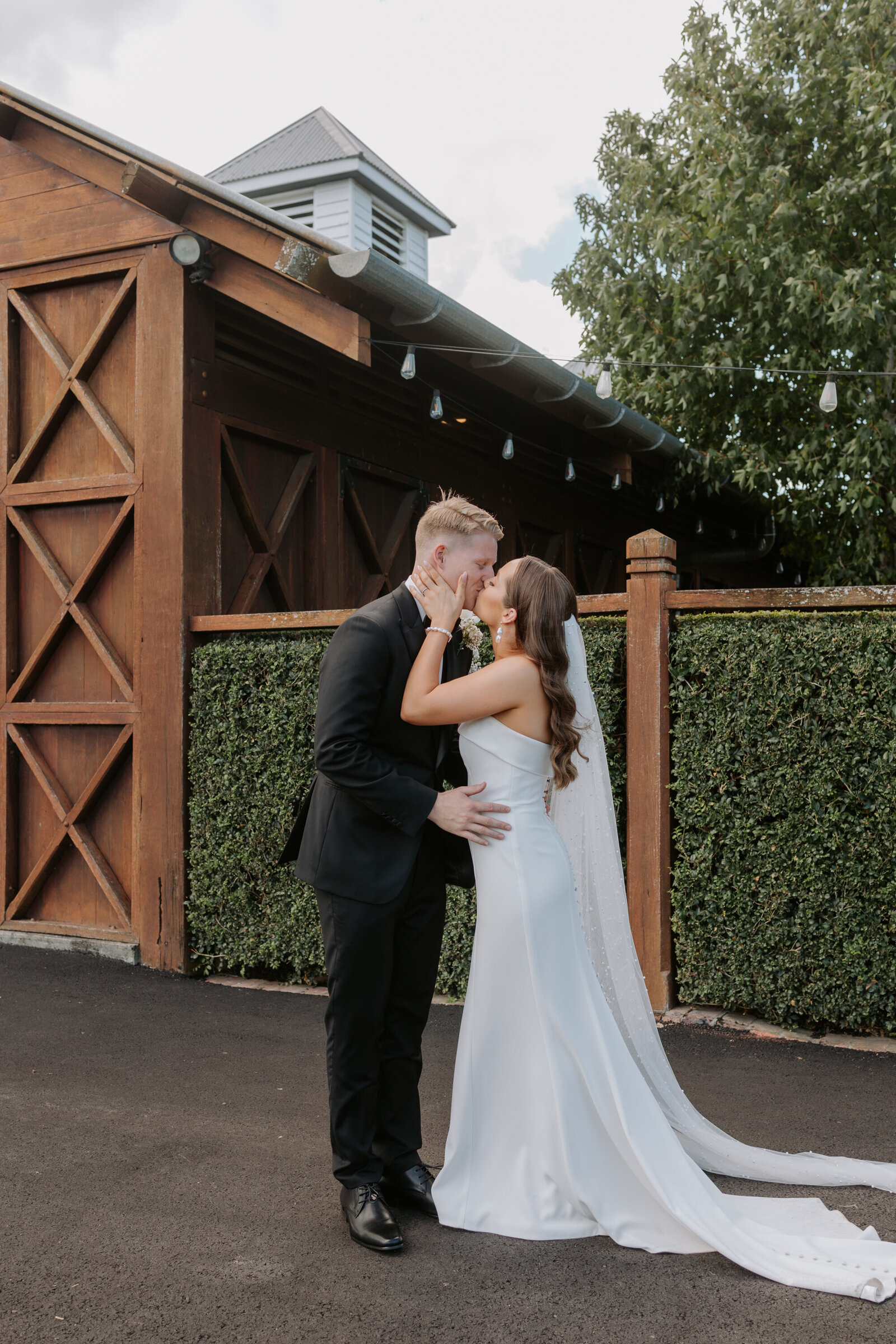 couple kissing in front of barn