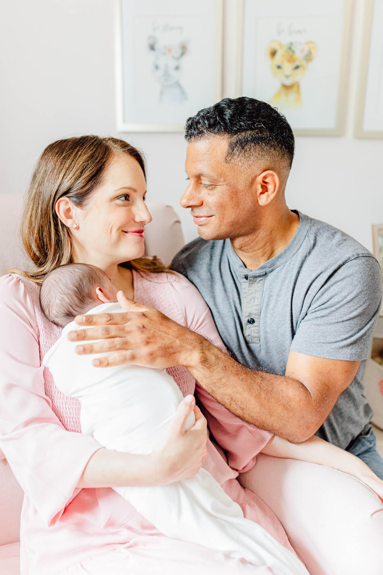 Mom cradles newborn and dad sits next to her, patting the baby's back