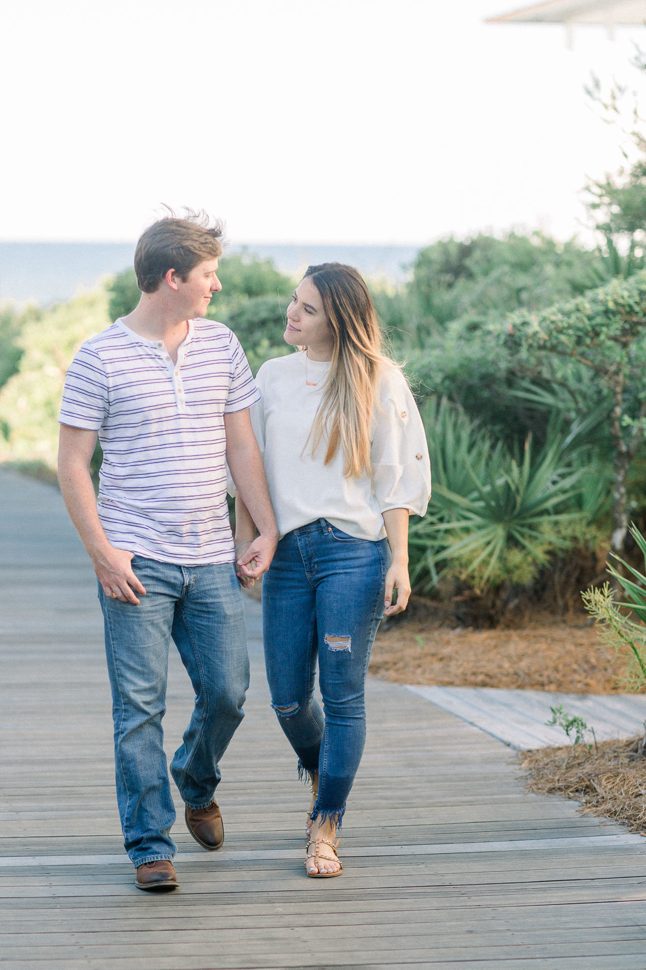 Couple holding hands and walking by the beach captured by Staci Addison Photography