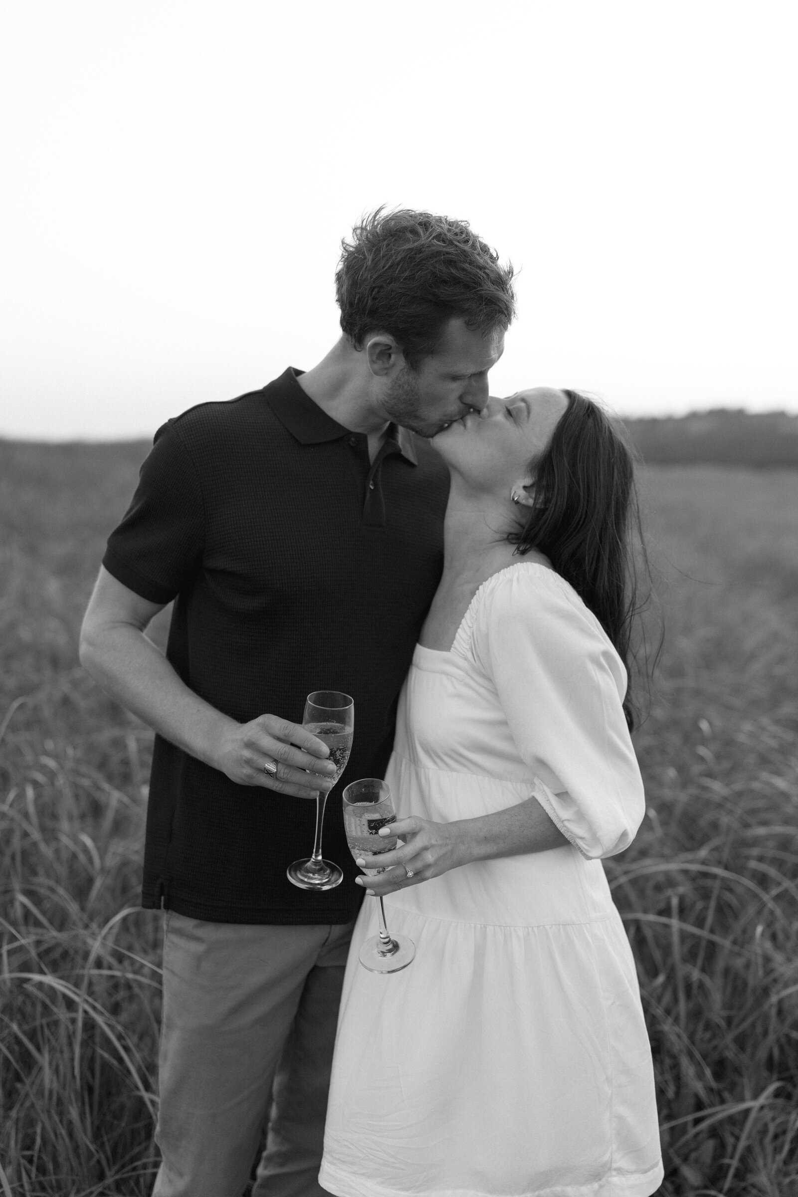 A couple shares a champagne toast to end their engagement session at Conrad's beach in Nova Scotia. 