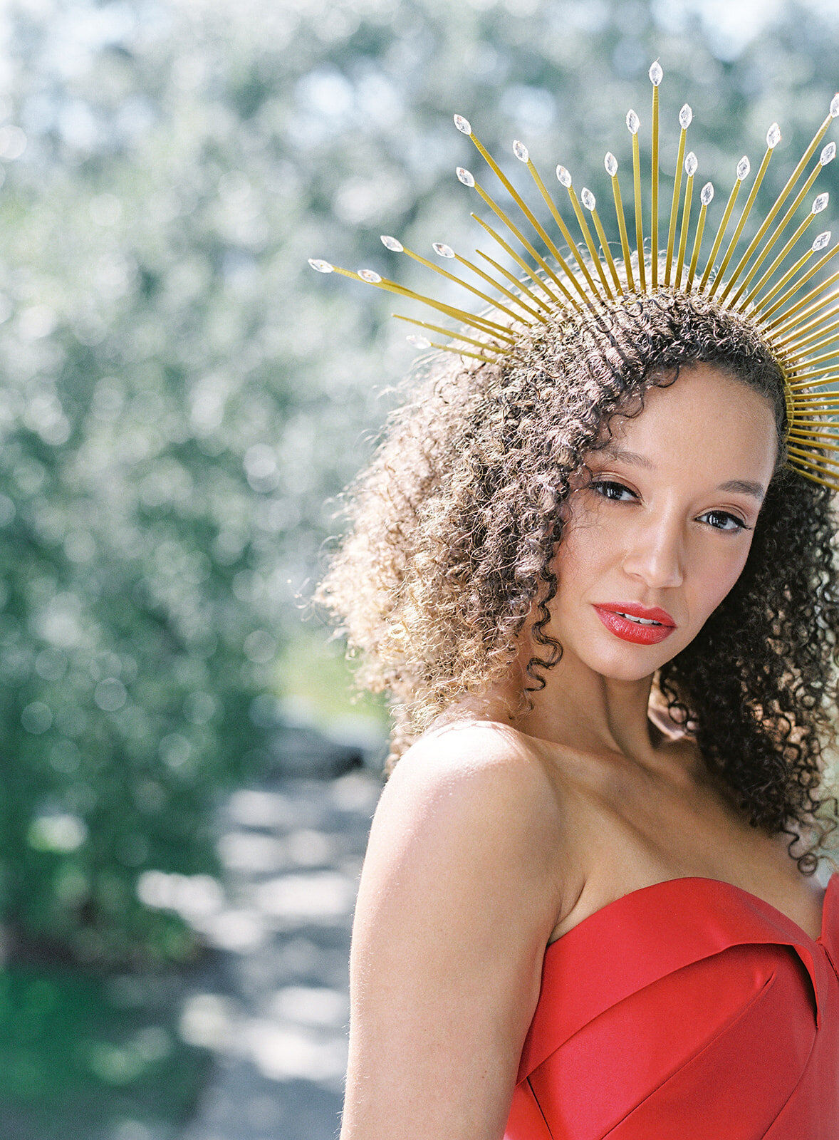 Bride in red wedding gown with gold sunburst crown. Her hair is fully down in her natural curls. She has scarlet red lipstick matching her dress by Anne Barge. Photographed by wedding photographers in Charleston Amy Mulder Photography.