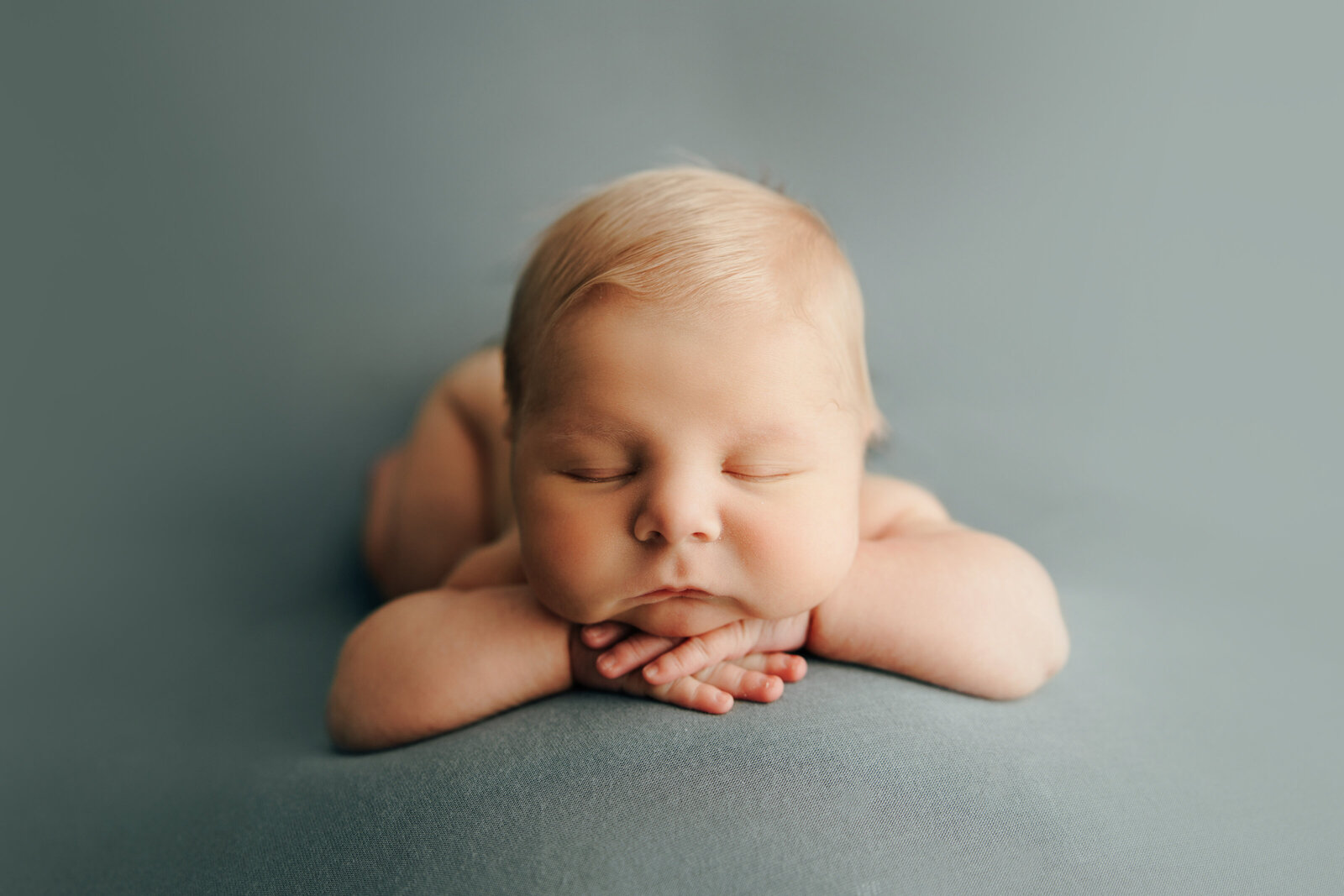 A blonde baby poses for a newborn photo