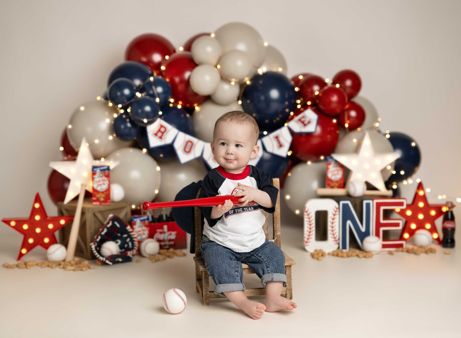 Baseball cake smash set with baby boy holding tiny bat. Studio cake smash photo taken by Jenni Nikki Photography in Atlanta, GA.