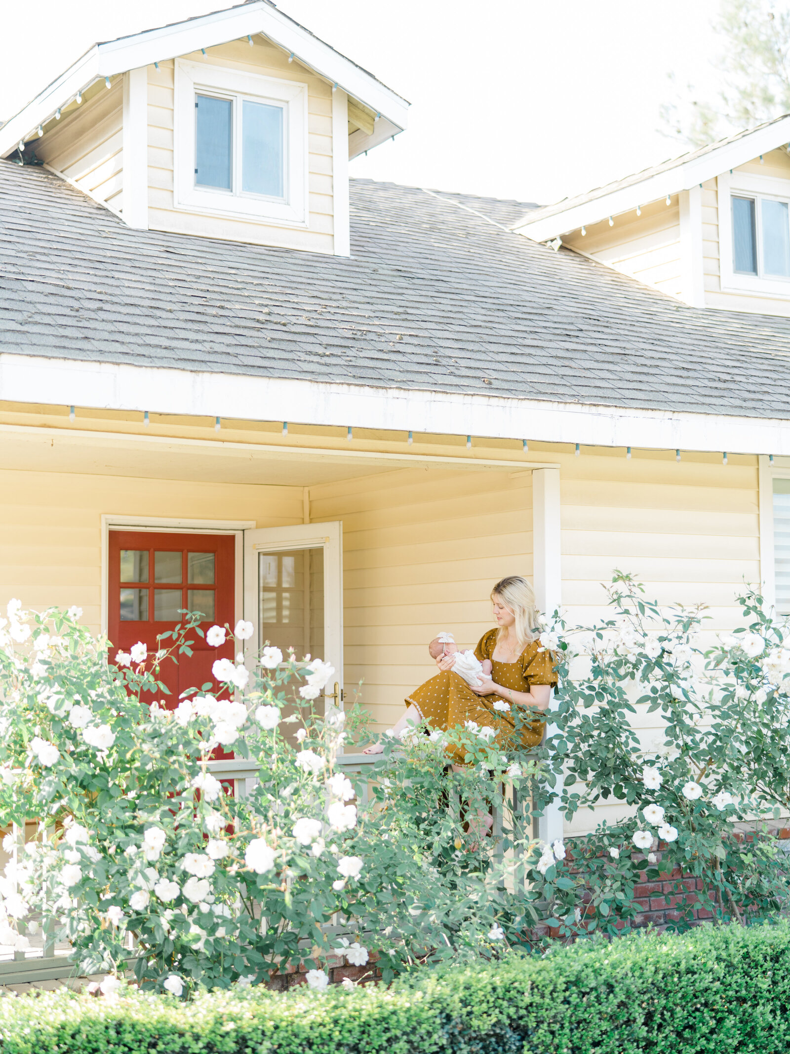 mother sitting on a porch and holding her new baby