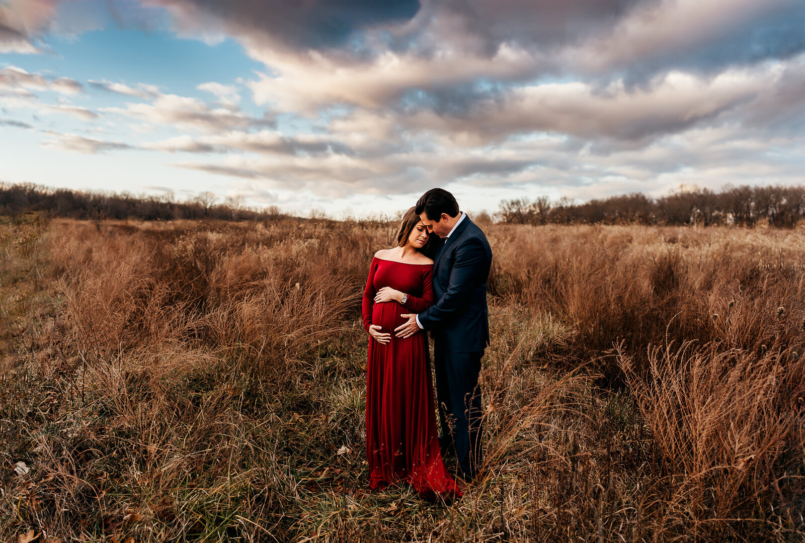 maternity couple standing in field