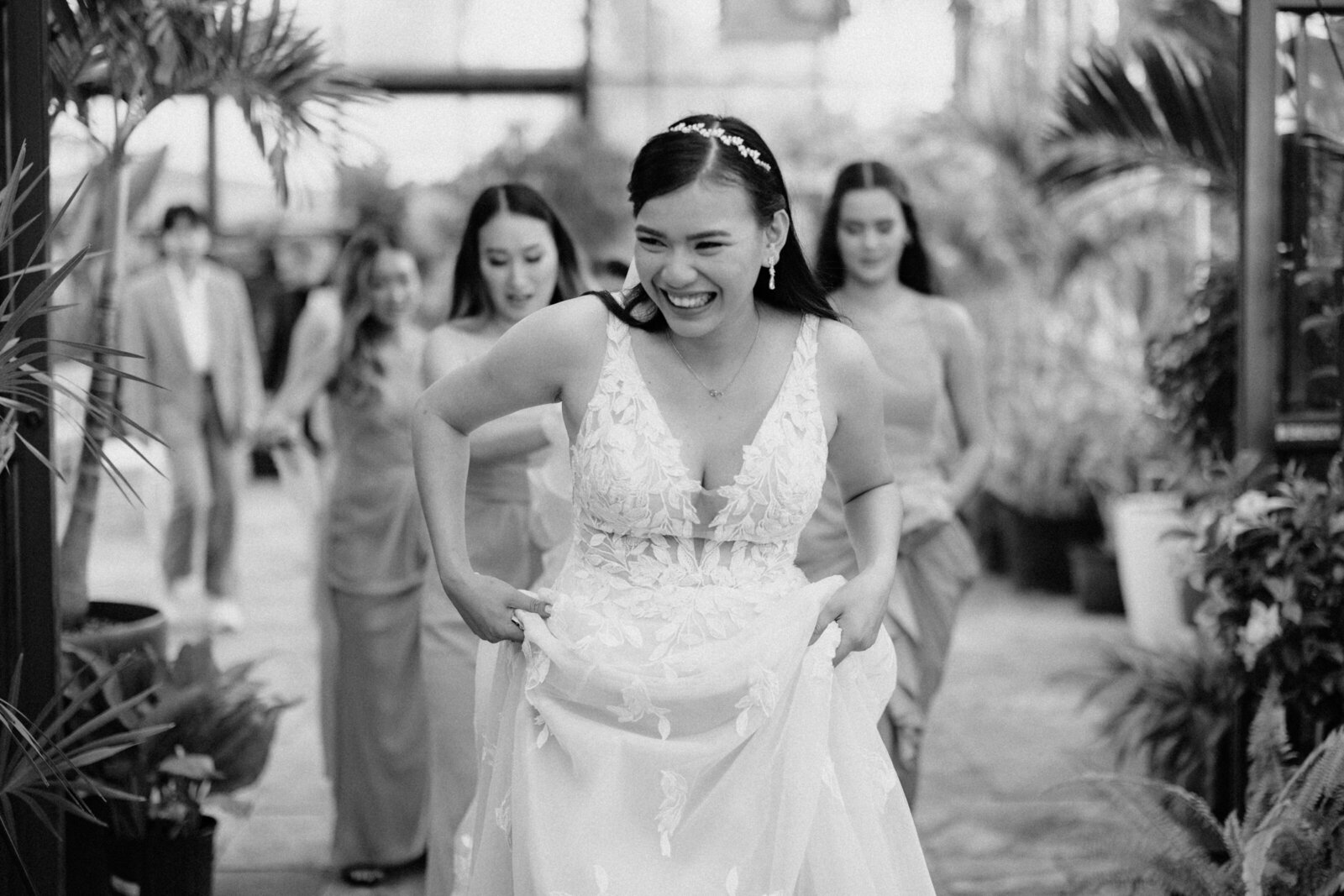 The bride walking towards the aisle, with a big smile on her face and her bridesmaids lined up behind her.
