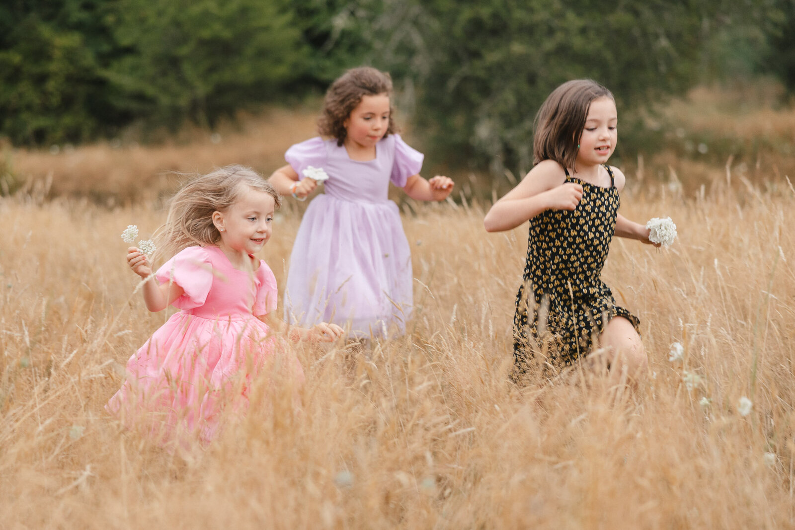 Kids running in a field wearing beautiful dresses at wedding in Vashon Island.