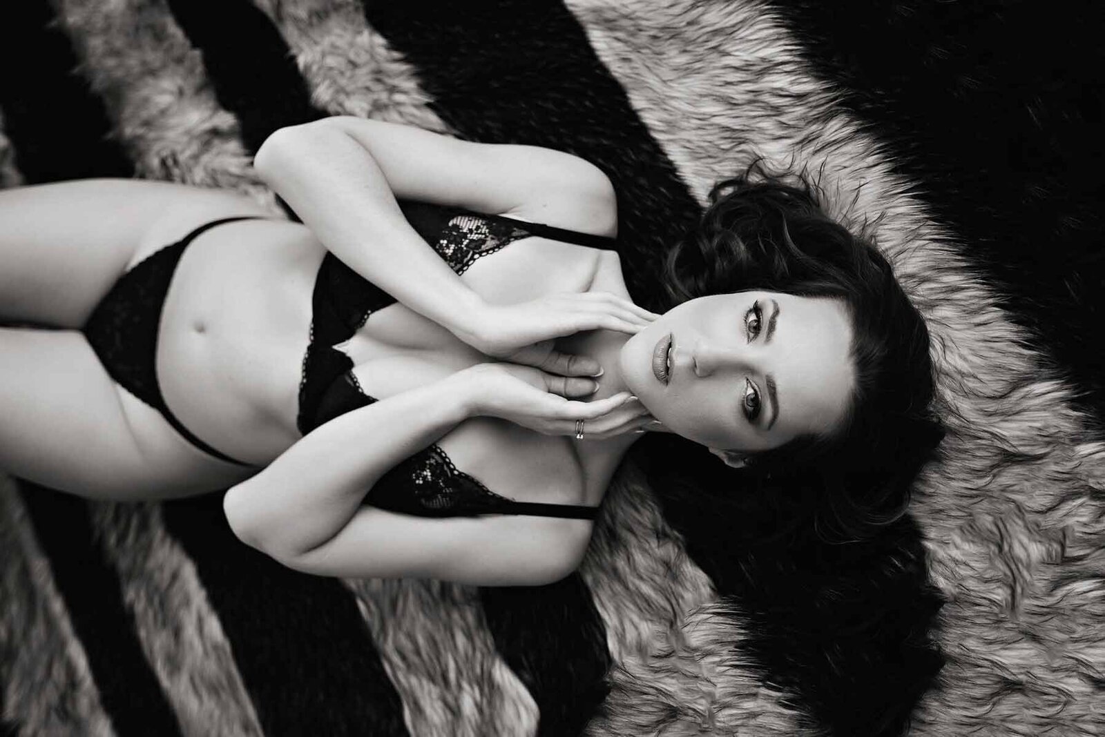 Black and white boudoir portrait of woman laying on striped rug