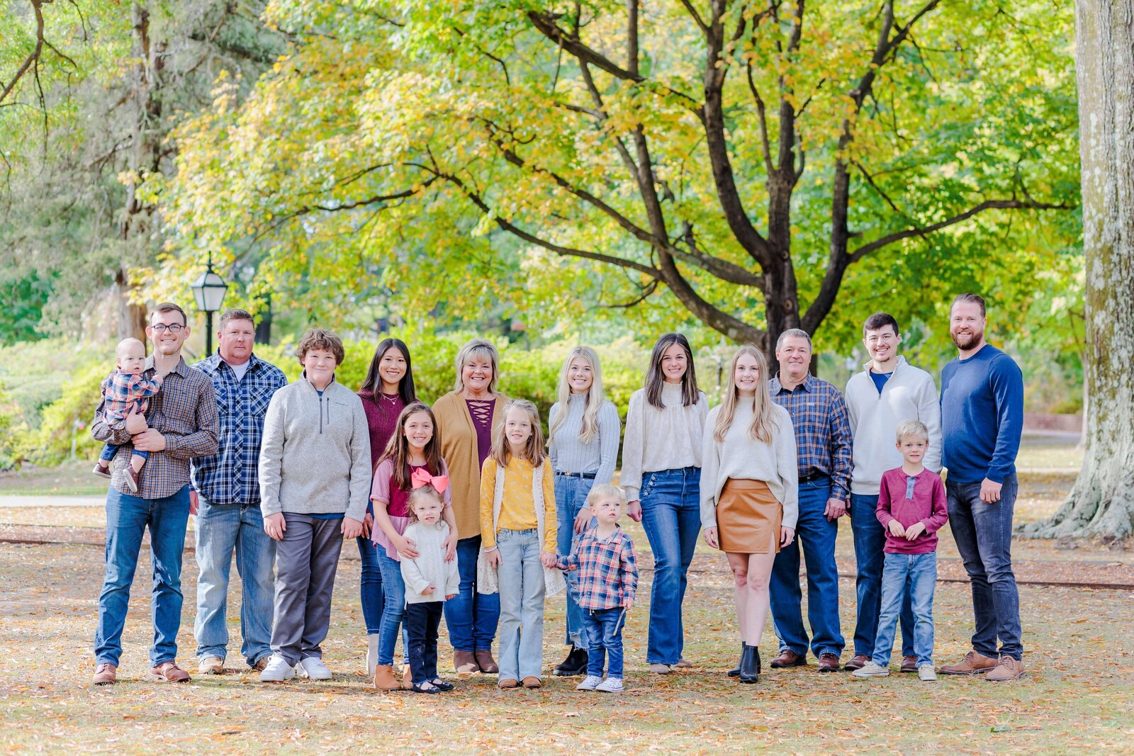 a large group family stand in front of a tree