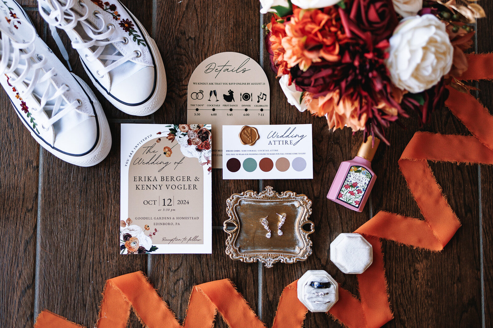 Wedding details and invitation suite strategically styled with orange ribbon and florals