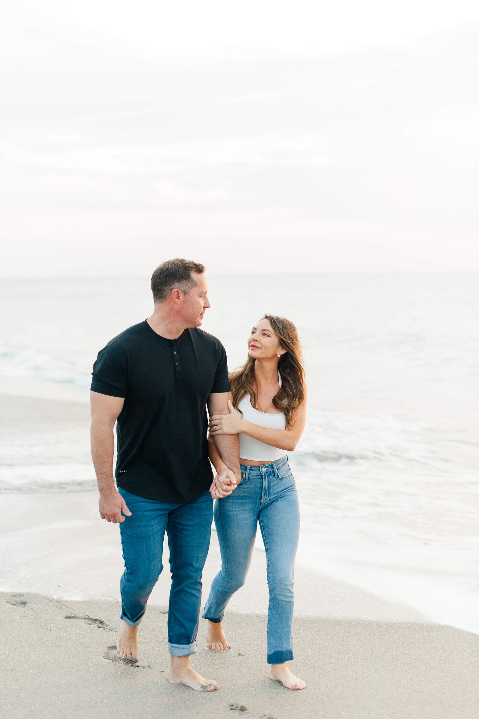 Adorable couple walks on the beach during their engagement photography session