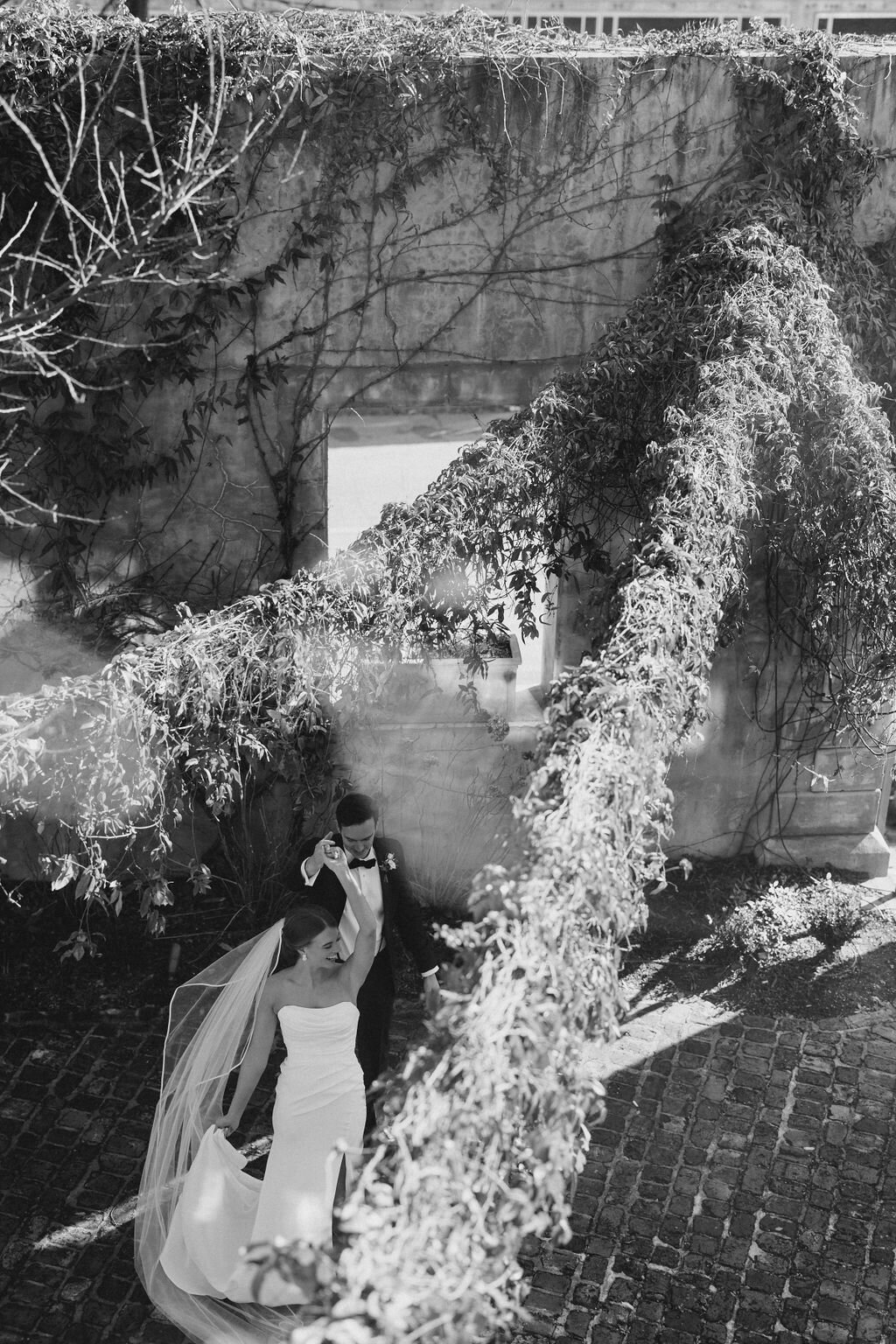 Groom twirls bride under stone archway at Summerour Studio