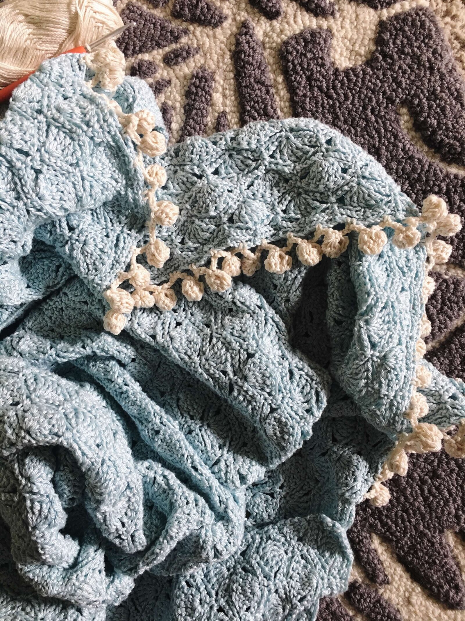 Light blue crochet blanket with off white bobble trim