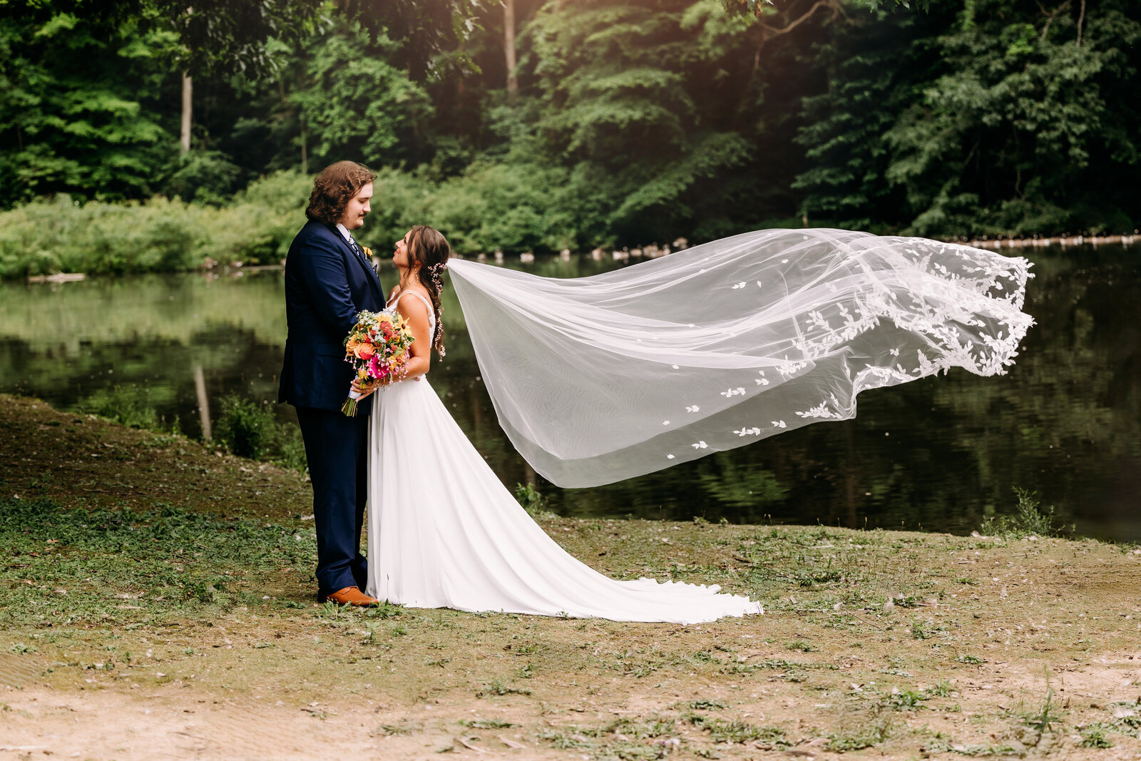Dynamic shot of the bride's flowing veil  in front of beautiful pond