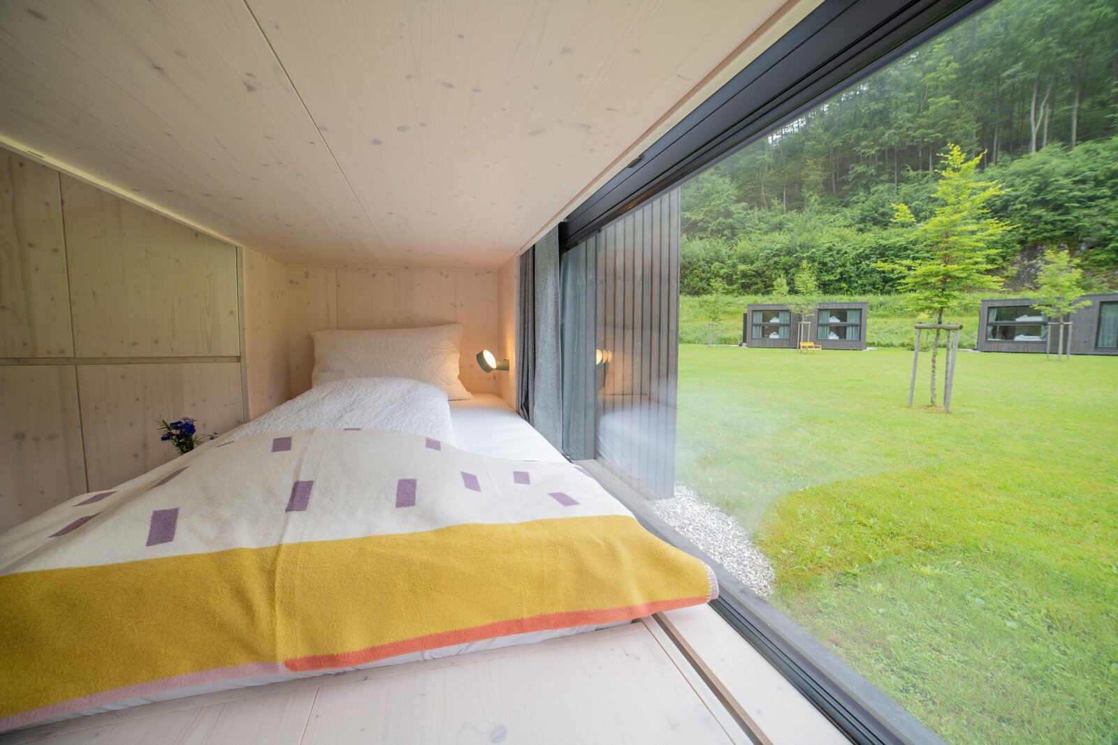 View of a cozy bunk bed with fresh linens inside a Tiny Home at The Campus Alps.com, offering comfortable accommodation