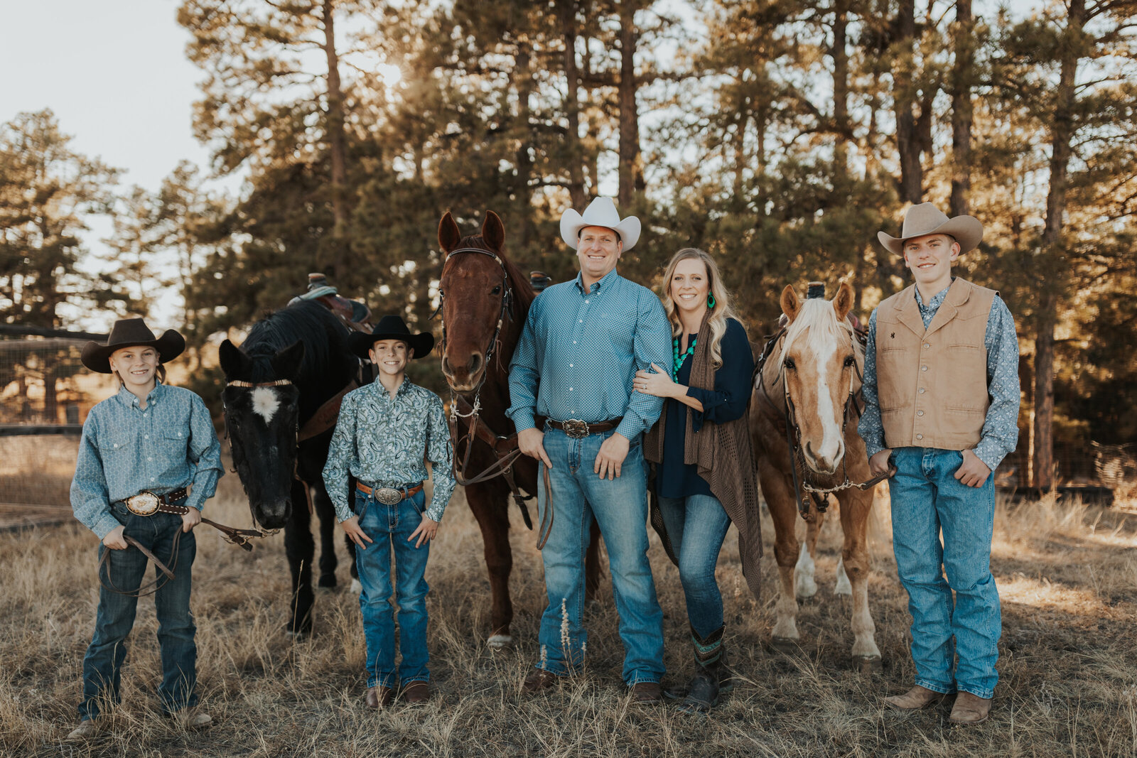 Mom, Dad, and Kids posed with their horses in families backyard