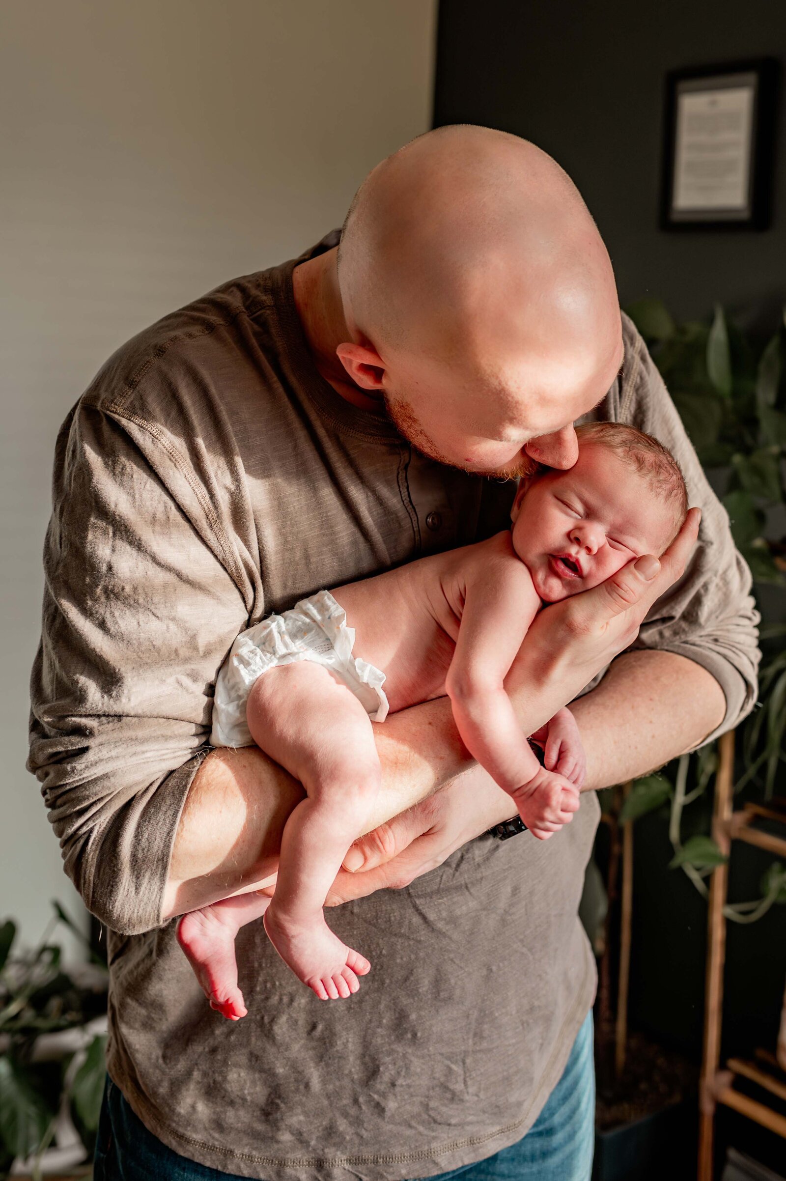 dad kissing newborn baby head