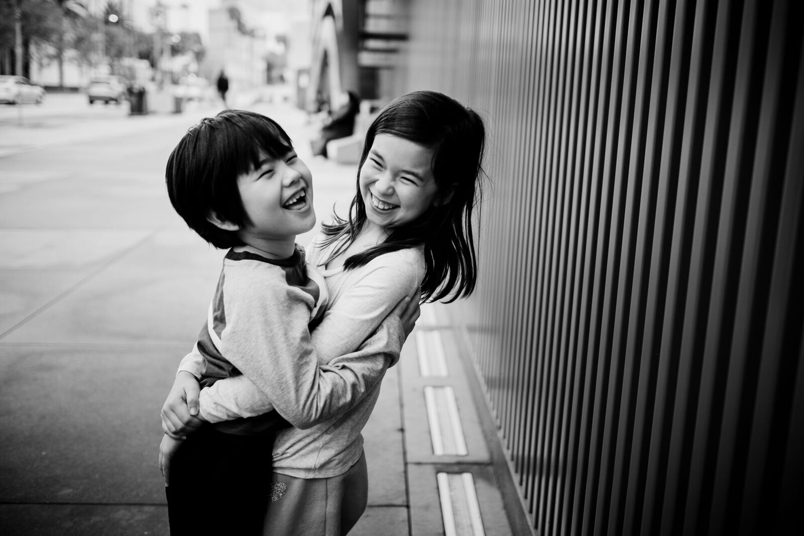 siblings hug each other playfully in a black & white image