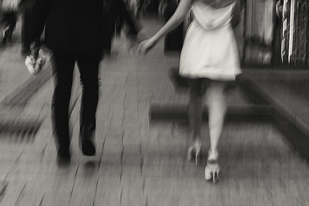 out of focus image of eloping bride and groom's legs holding hands walking away. energetic