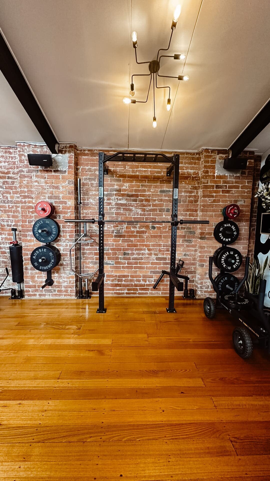 Weight racks at beautiful gym in Collingwood with wooden flooring