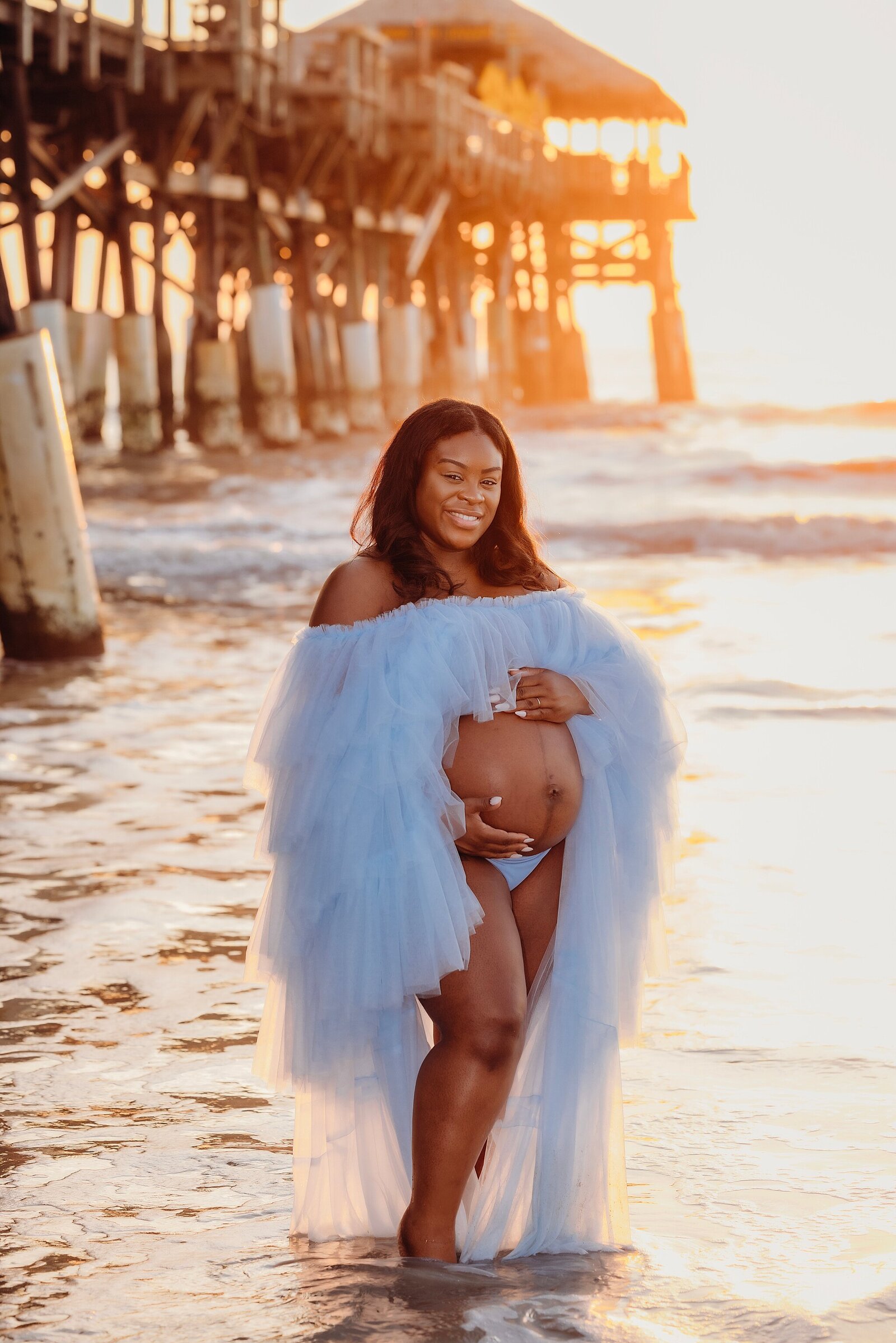 Sunrise maternity photography by Bia Schaefer in Cocoa Beach, FL, showcasing the beauty of motherhood in a serene setting.