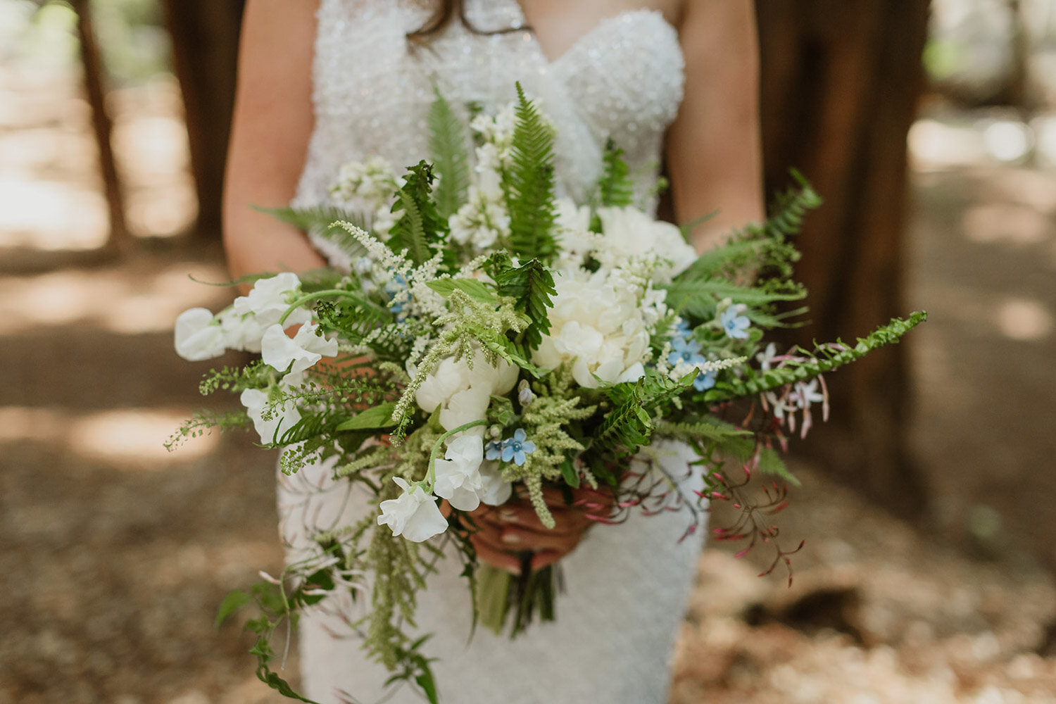 Bride holding bouquet with white roses and ferns