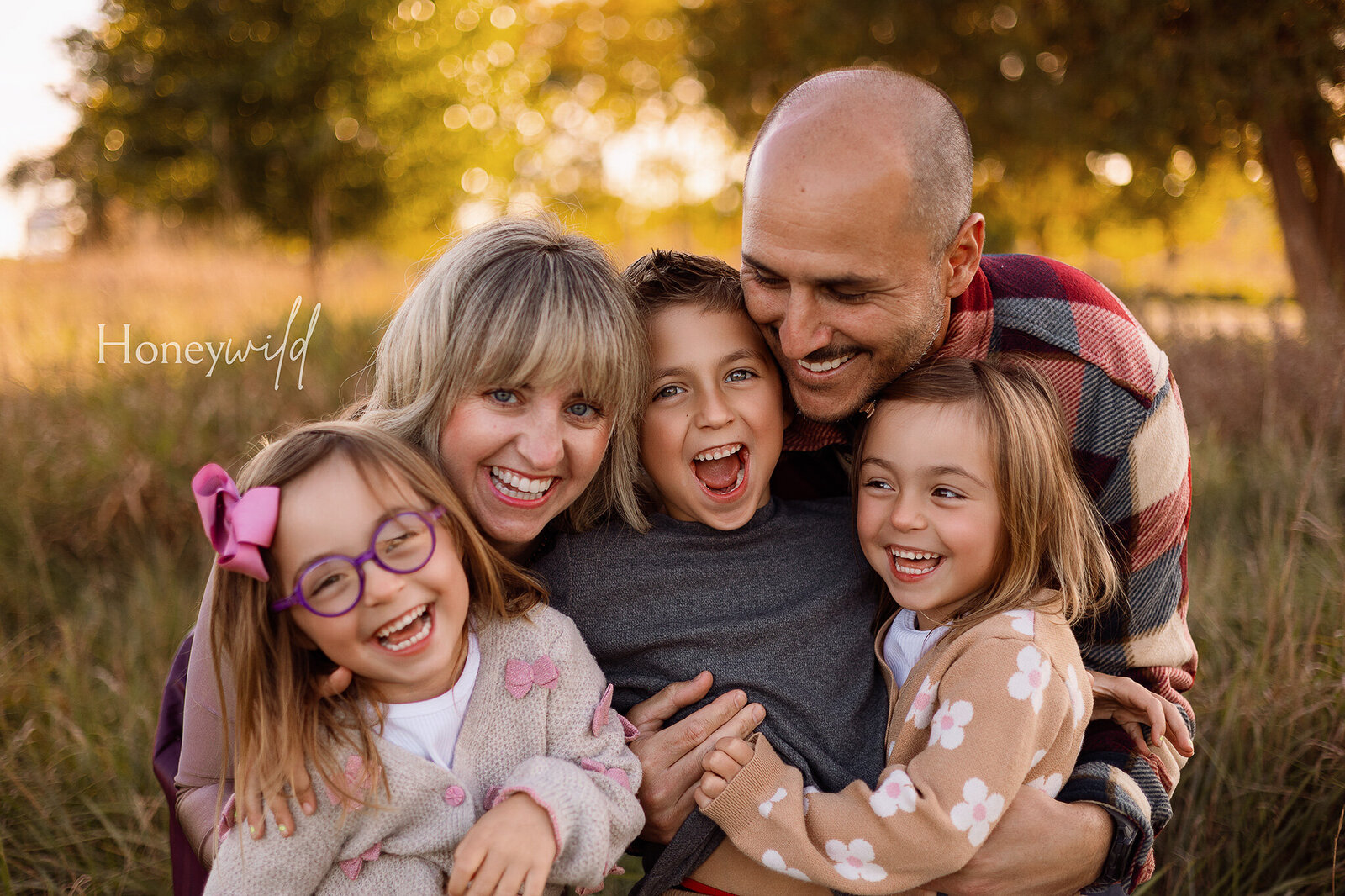 A happy family of three enjoying an outdoor photography session in Grand Rapids, Michigan, with a mother and father holding their smiling baby in a scenic natural setting.