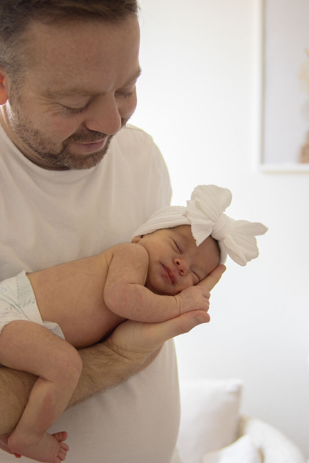 Father holding his newborn baby with a large white bow