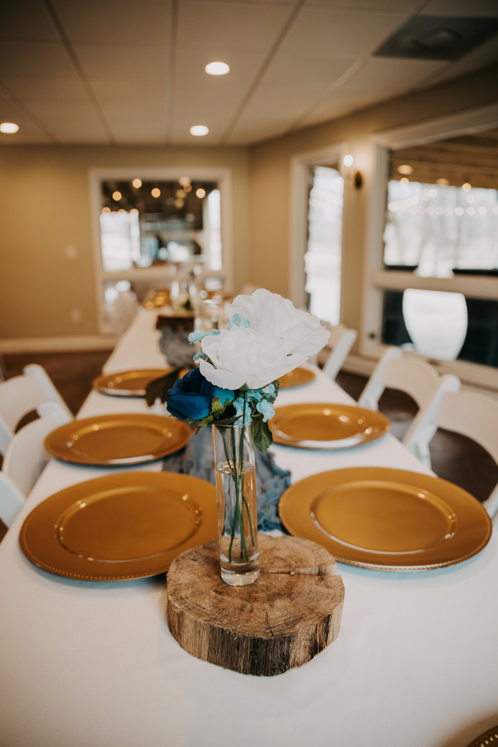 Bridal party table at Kincaid Manor with golden plates and flowers in a vase, creating an elegant reception setting.