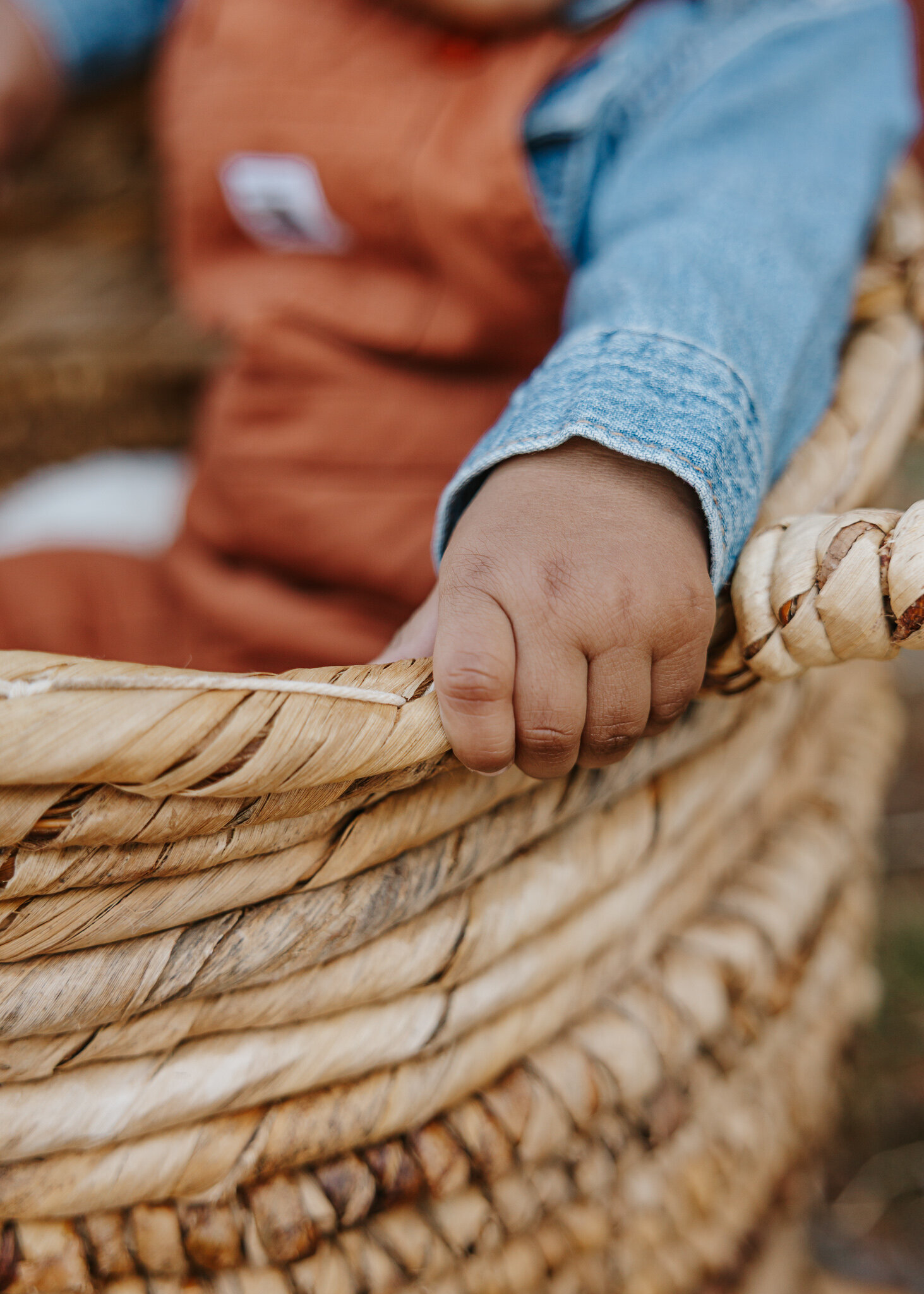 Close-up of a baby's hand resting on a woven basket during a 6-month to 1-year milestone photoshoot in Hephzibah GA at Tripp Ranch.