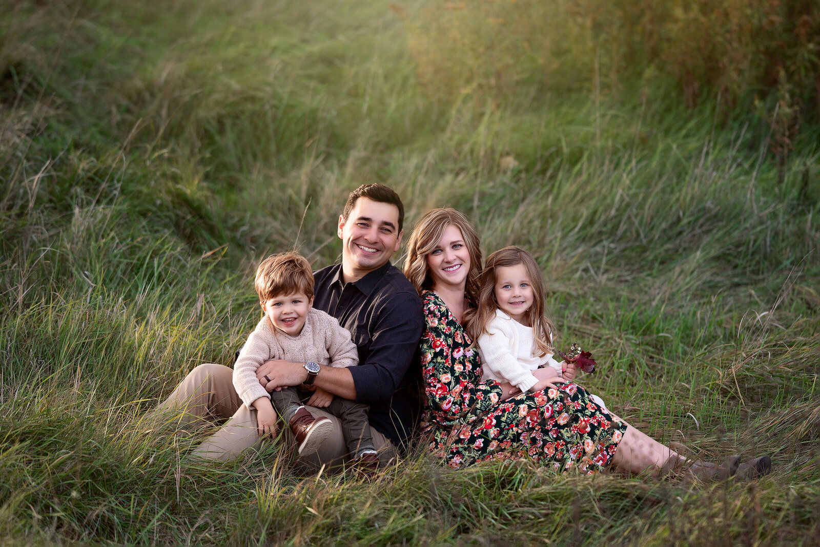 Family of 4 sitting in tall grass at their Detroit Family Photography session with Kat Figlak