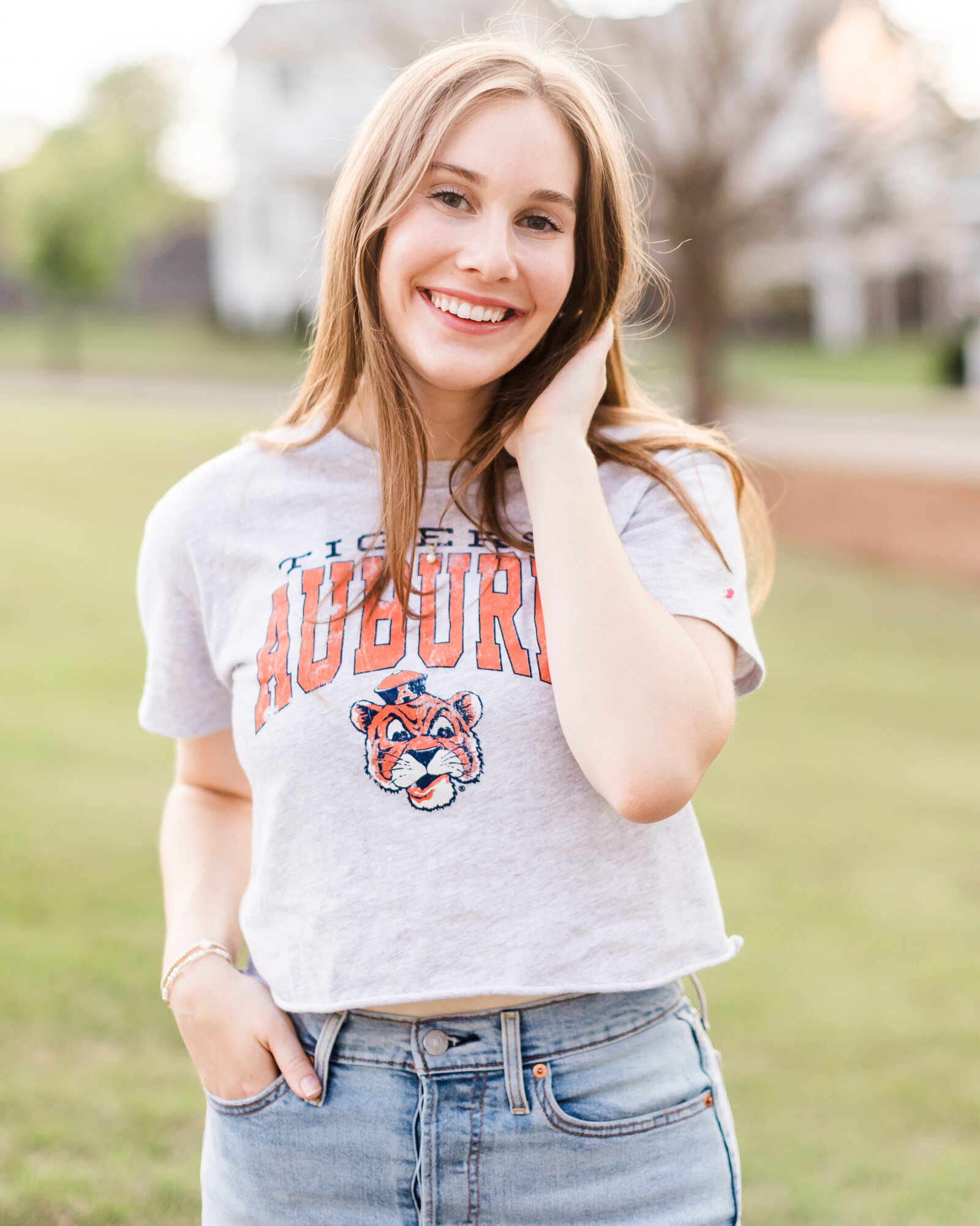 Sophie posing in a cropped Auburn Tigers shirt, radiating joy during her senior portrait session, photographed by Abby Bell Photography, Fine Art Portrait Photographer based in Alabama.