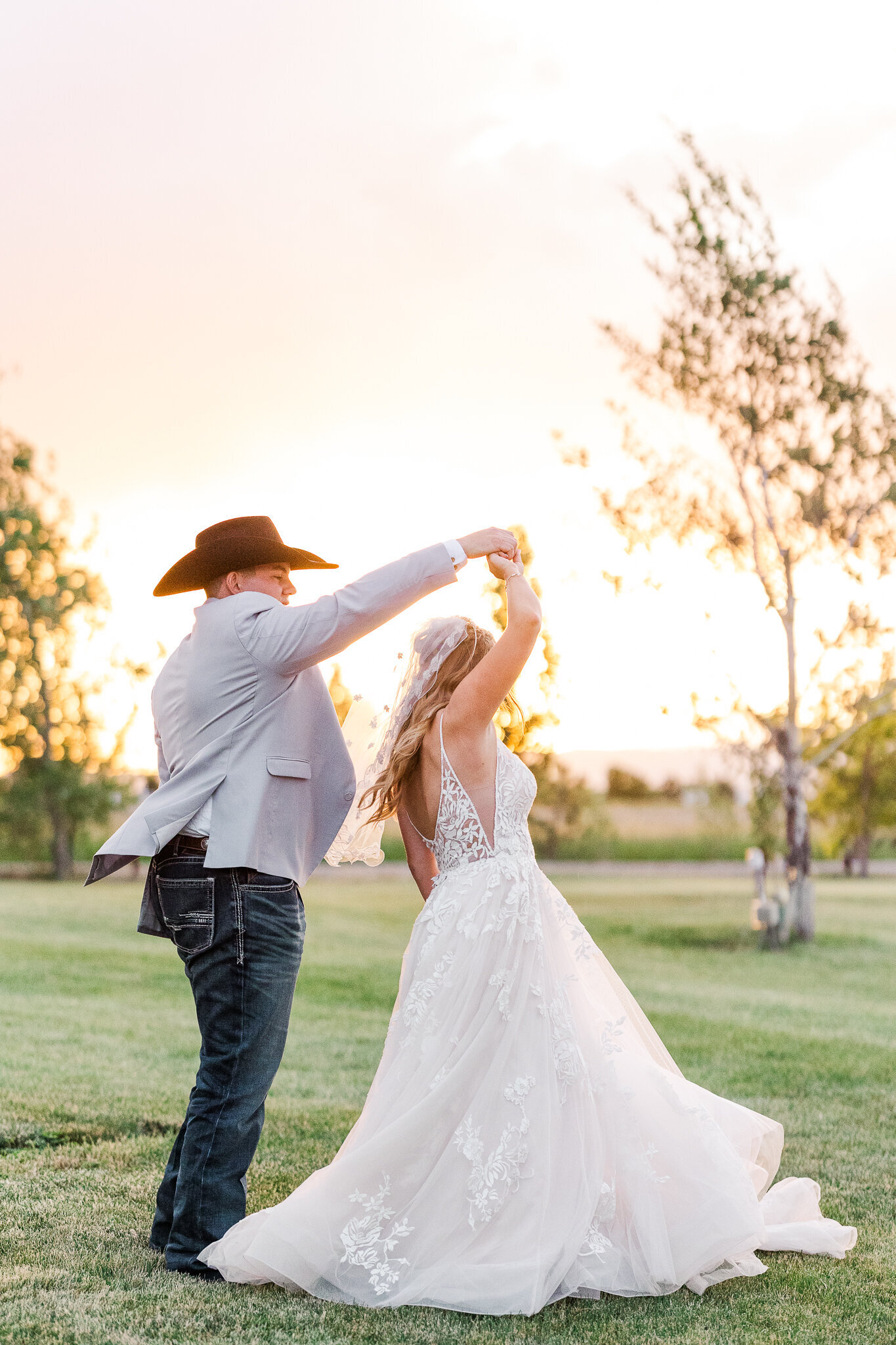 Groom spinning his bride joyfully during golden hour at Absolute Prestige wedding venue in Loma, Colorado