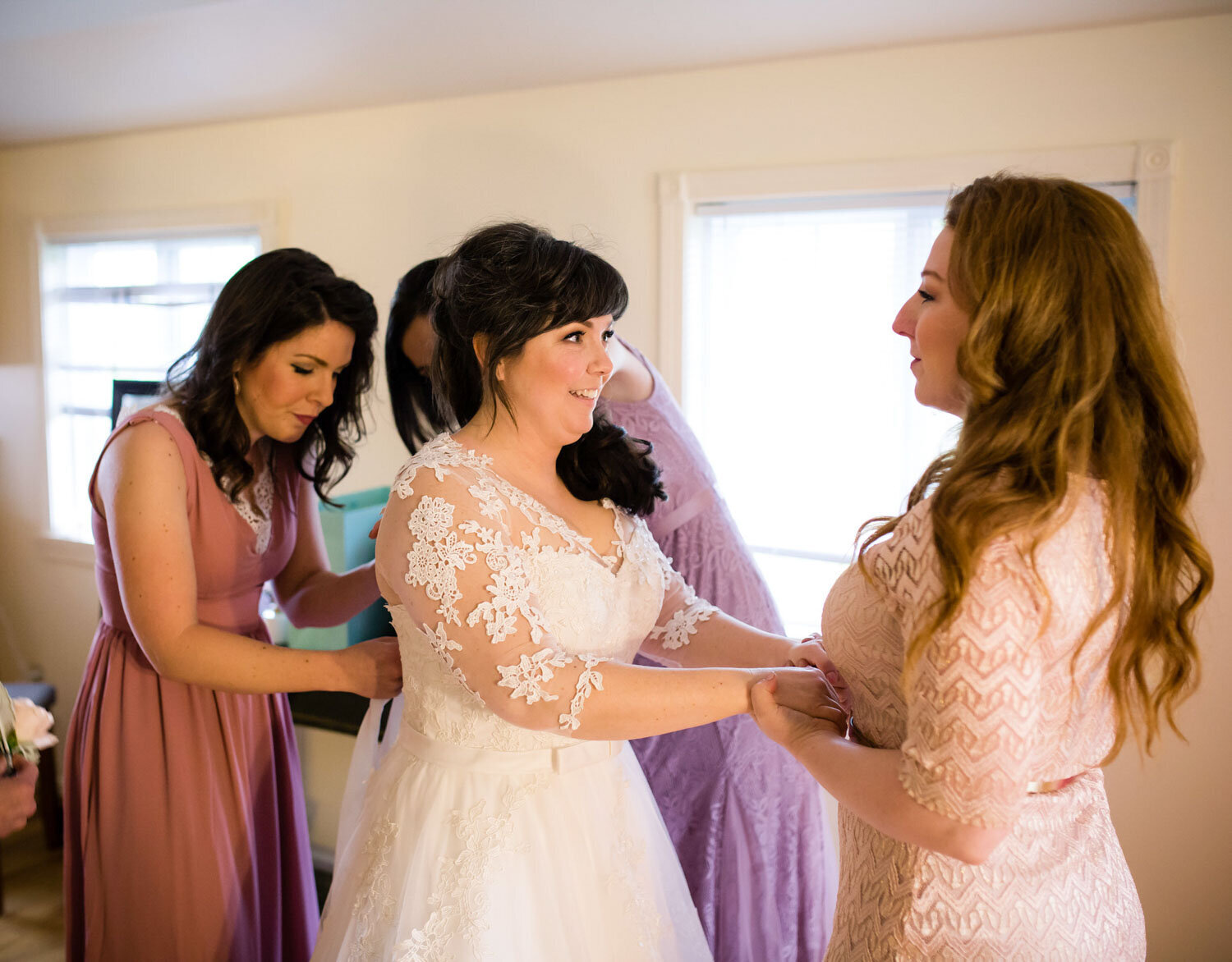 A bride surrounded by loved ones helping her prepare for her big day