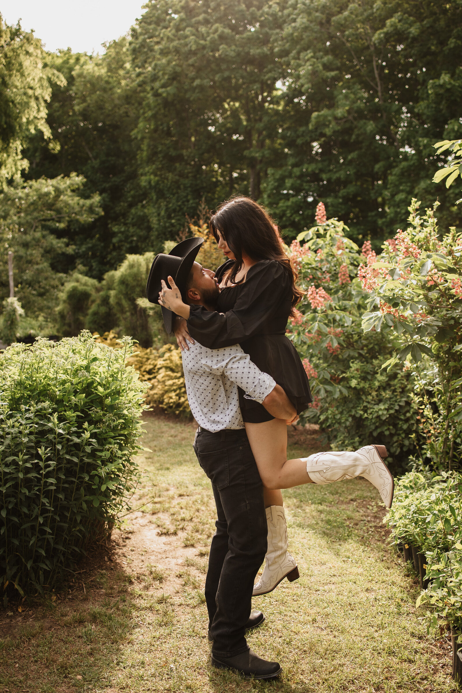 Fiance holds up soon to be wife at their engagement photos at the magical fairy garden of Peconic Herb Farm in Long Island, New York | Emma LeeAnn Photography