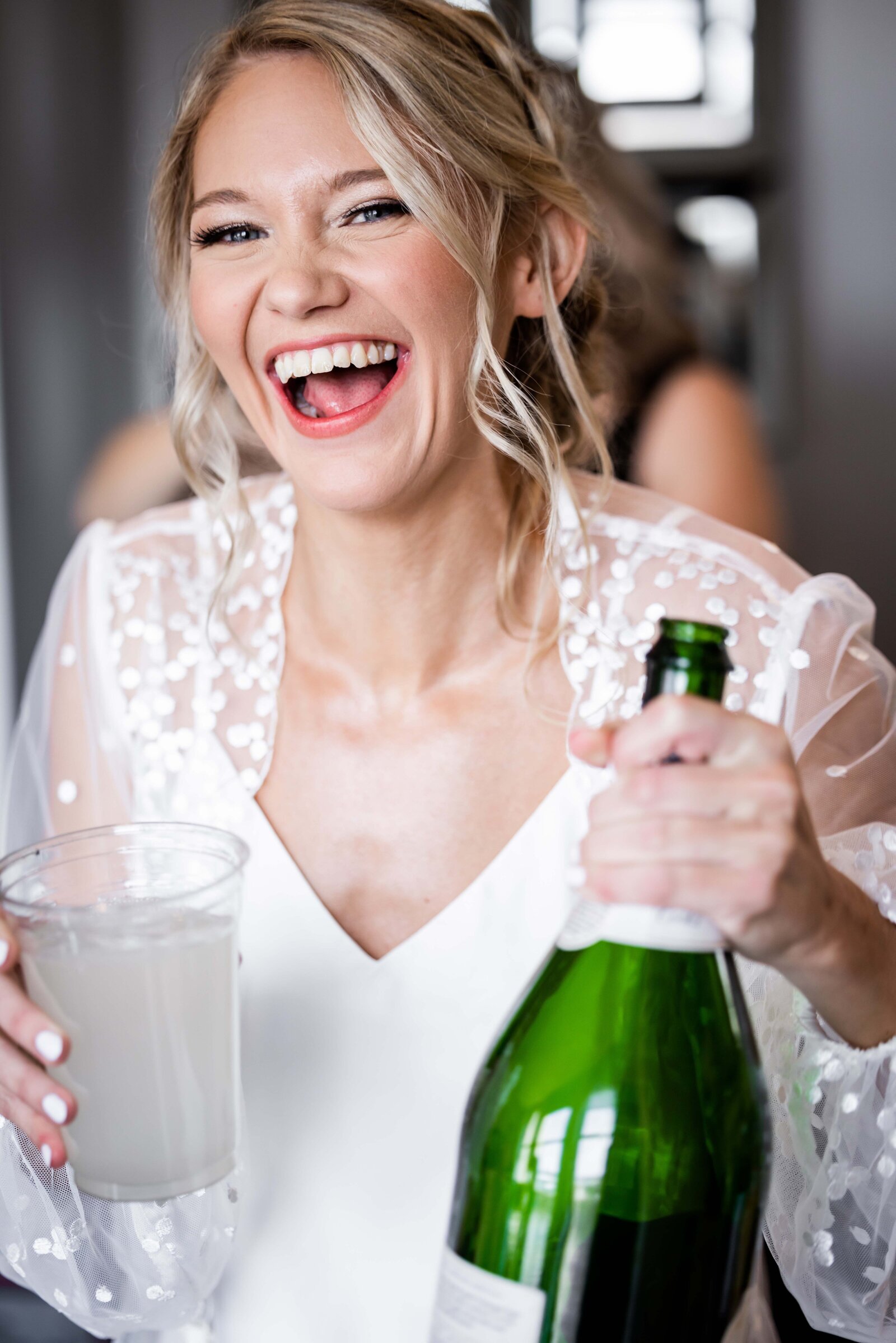 Capture the exuberant moment as Hailey readies to pop a bottle of champagne, symbolizing the start of her joyous wedding celebration. This vibrant image showcases the bride's anticipation and the festive spirit, perfect for couples seeking inspiration for their own celebratory moments. Embrace the blend of elegance and excitement that epitomizes a perfect wedding toast.