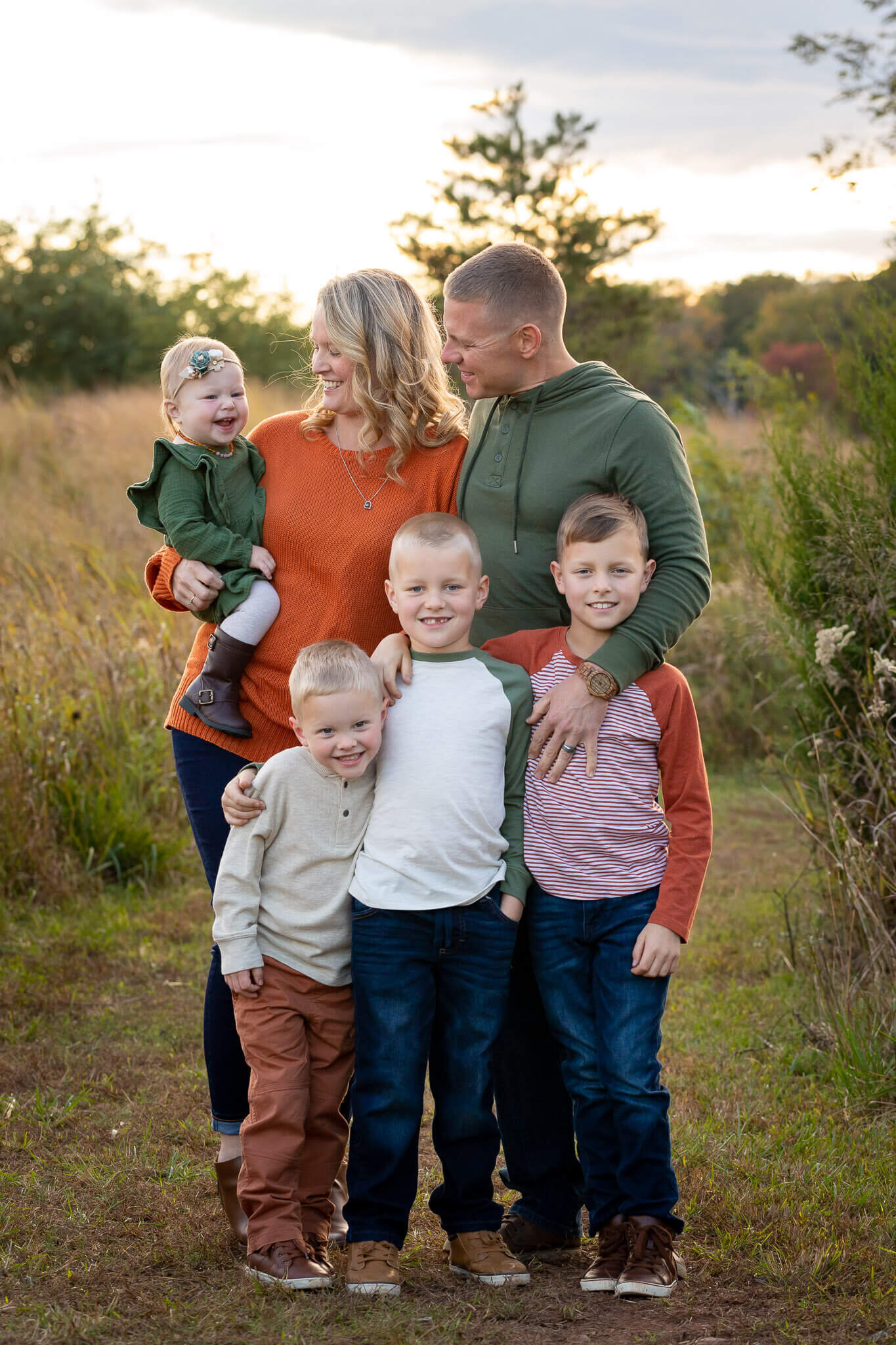A family with three sons and a daughter posing in a field at sunset for a Northern Virginia family photography session.