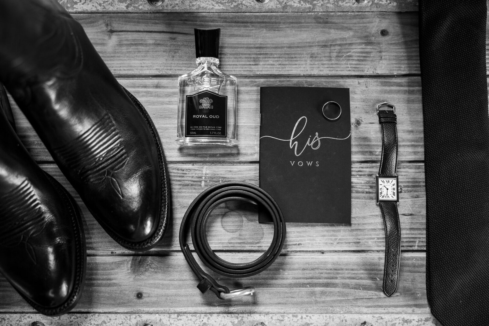 Flat lay of groom’s wedding day accessories including belt, cologne, wedding ring, and watch at SkyView Golf Club