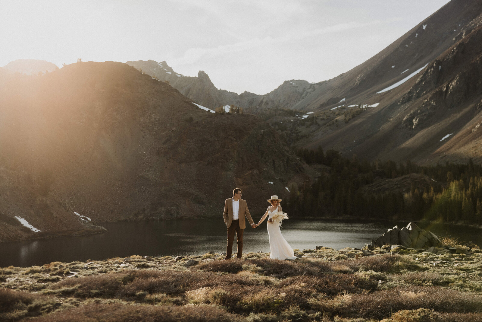 bride and groom holding hands in front of a mountain