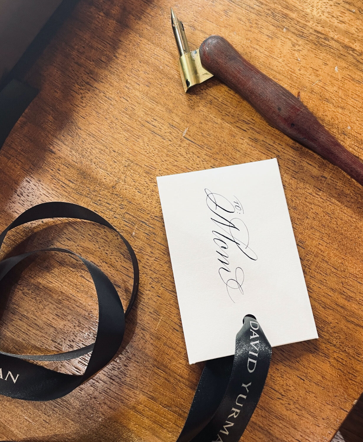 Small calligraphy note on wood, accompanied by a ribbon and nib pen