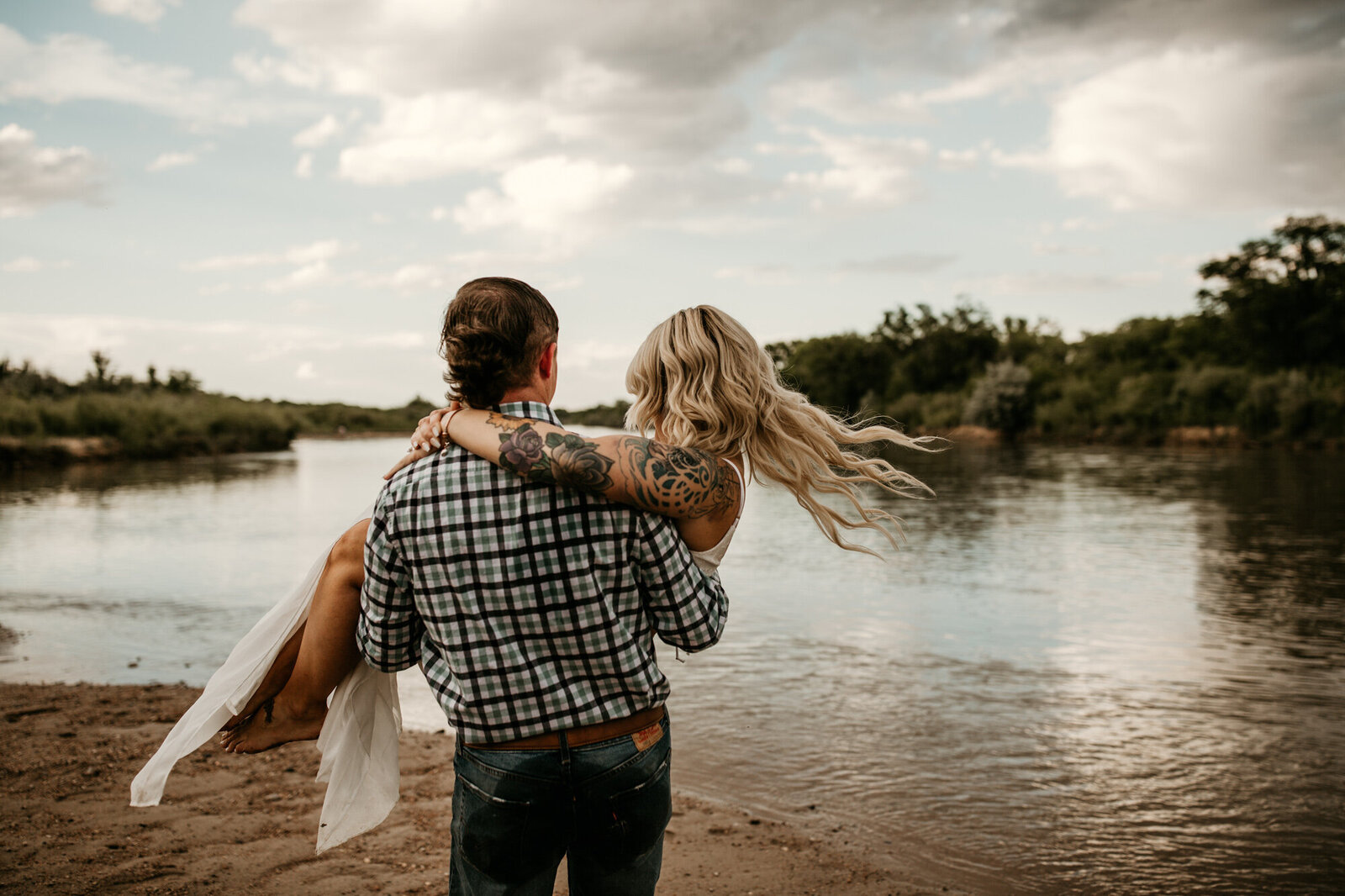 groom holding bride by a river