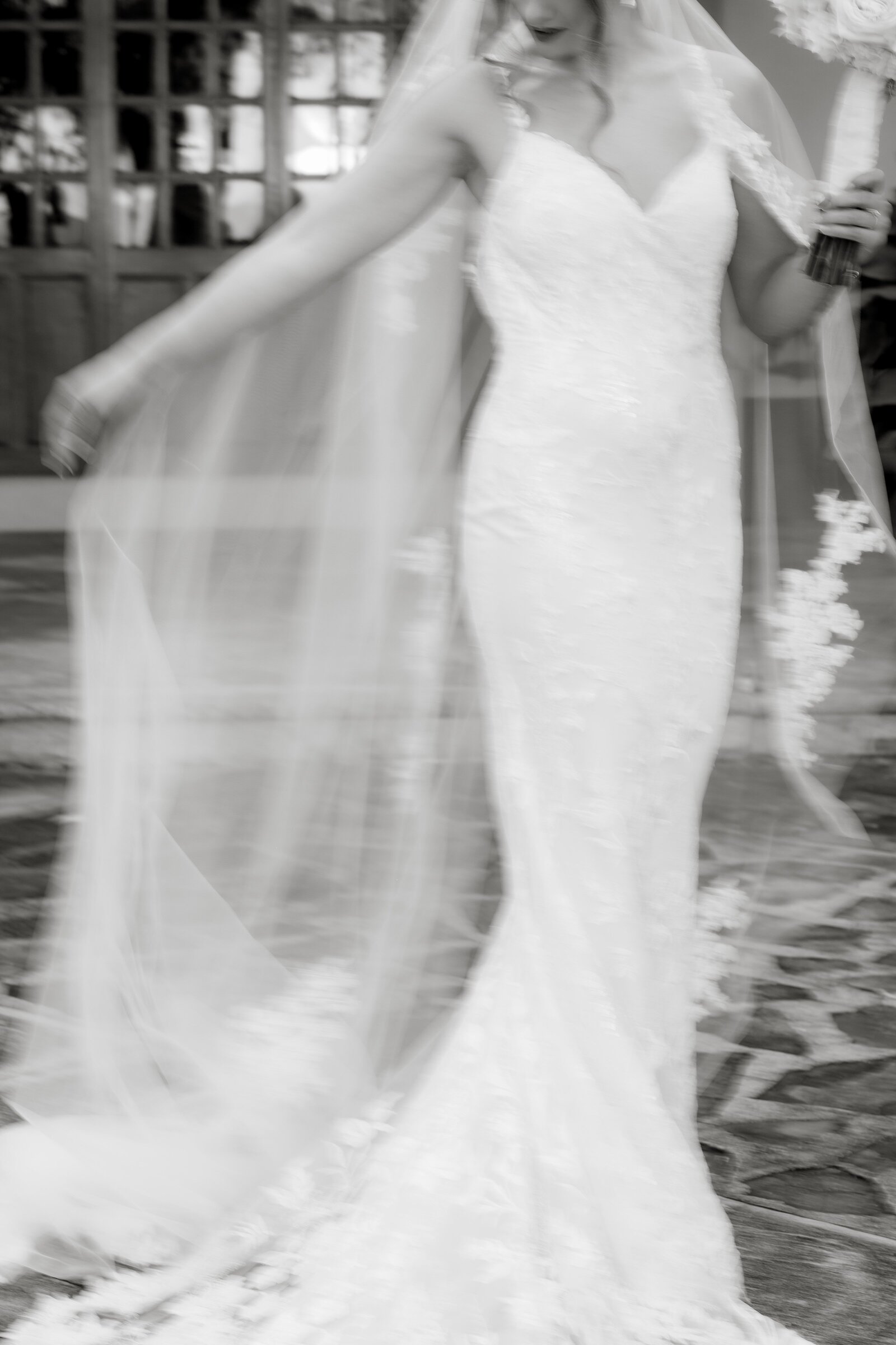 black and white image bride wearing lace wedding dress with long veil