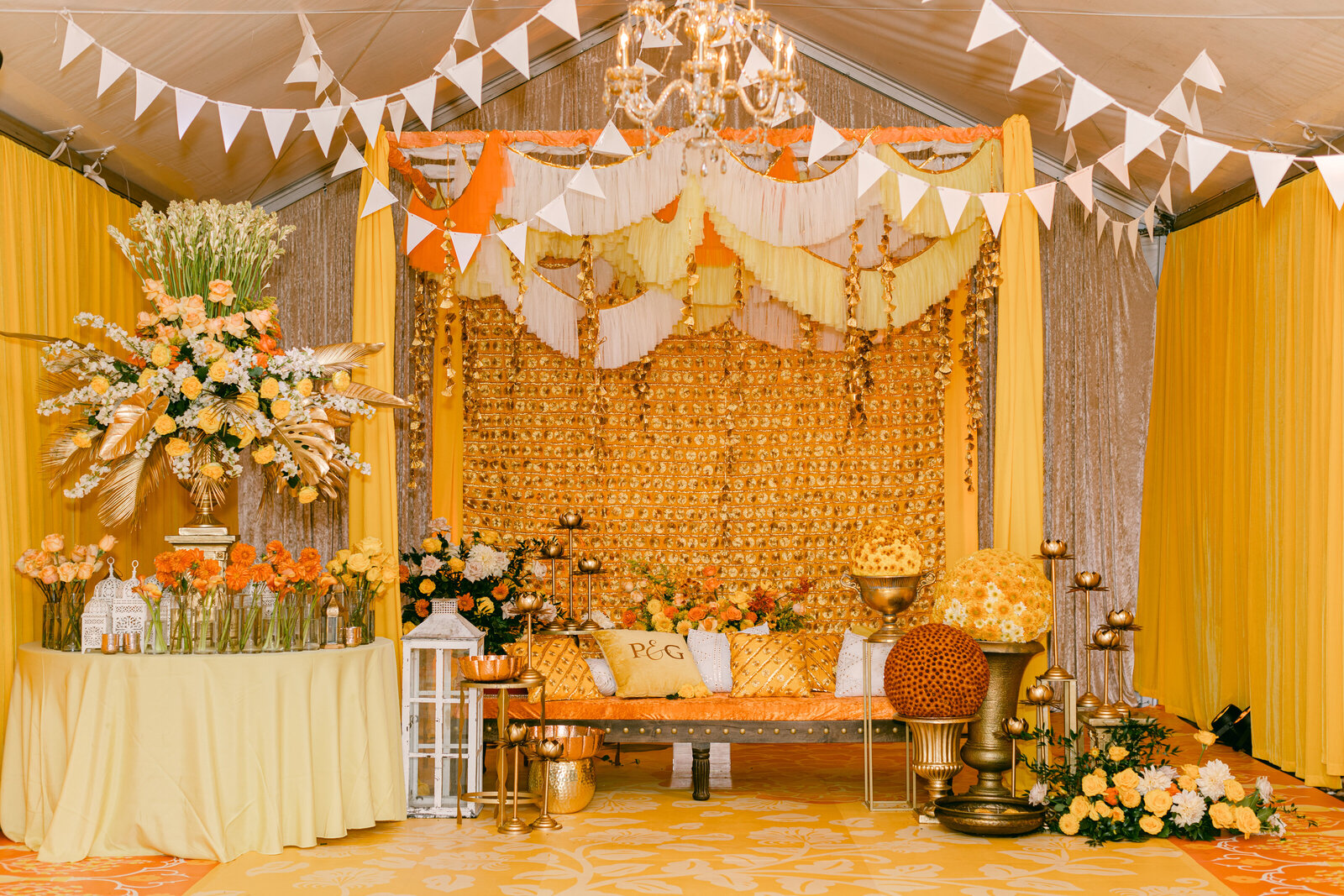 orange themed sikh wedding reception with yellow and orange florals on a gold table