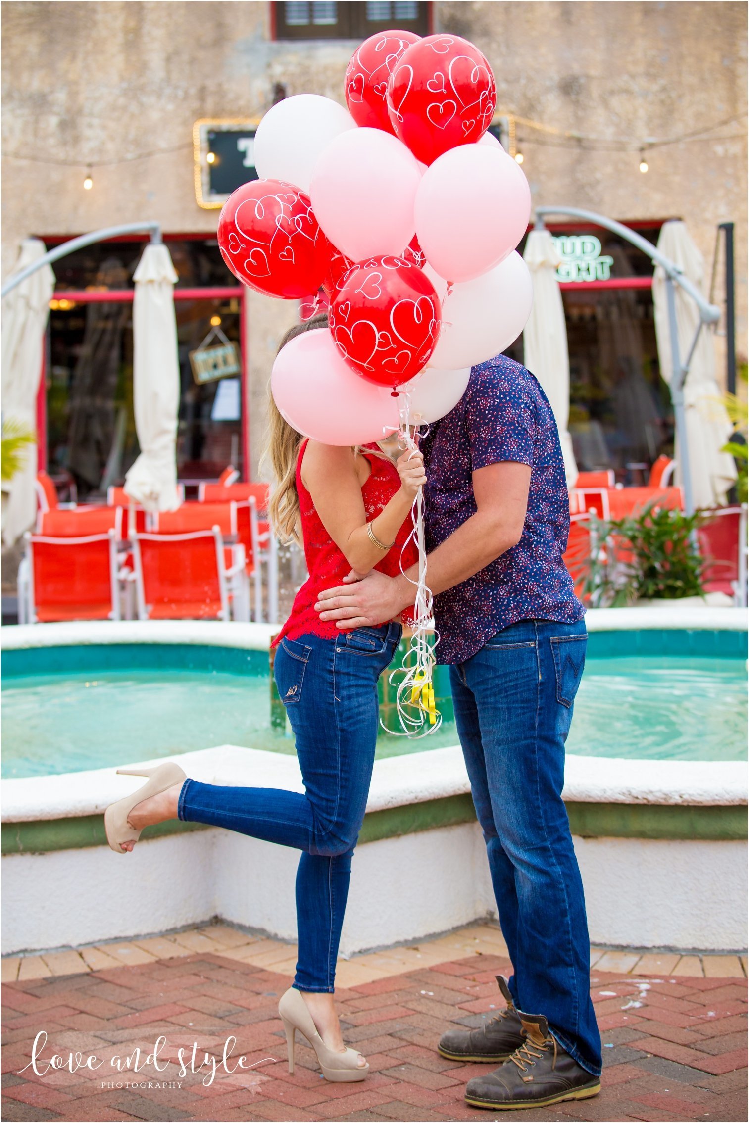 Sarasota Engagement Photography of couple kissing  behind red and pick balloons downtown