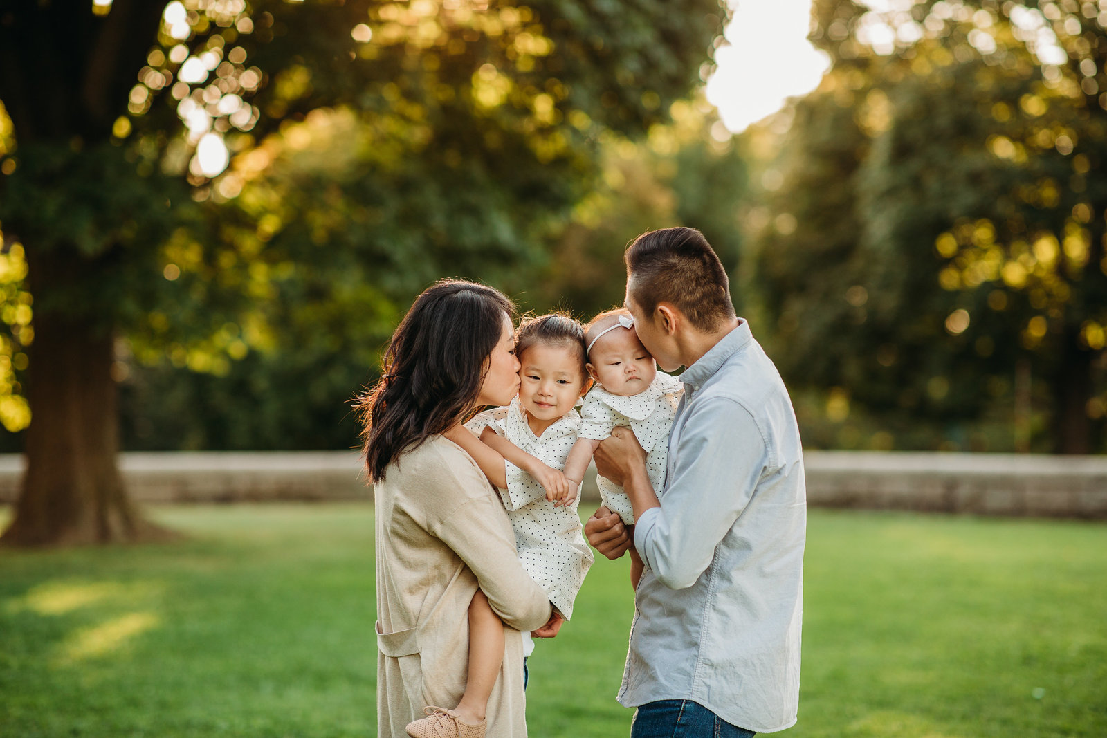 family snuggles two daughters outdoor during brookline family photos