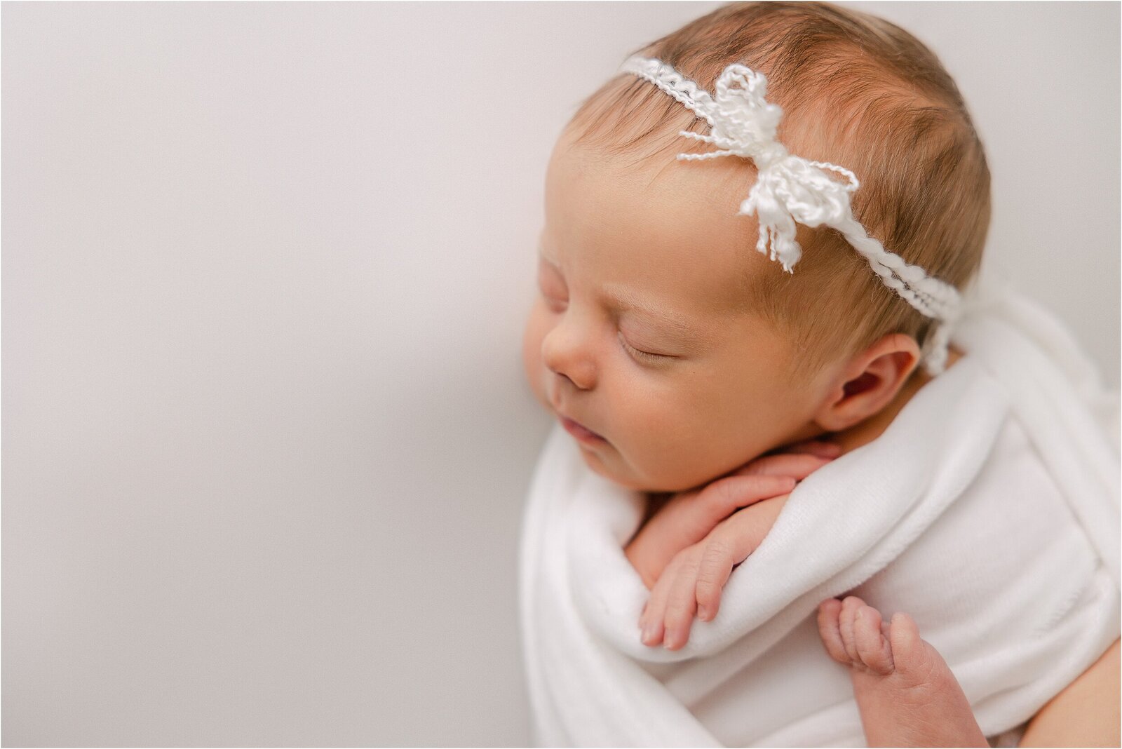 Baby girl in white bow and swaddle sleeping at her Indianapolis newborn session