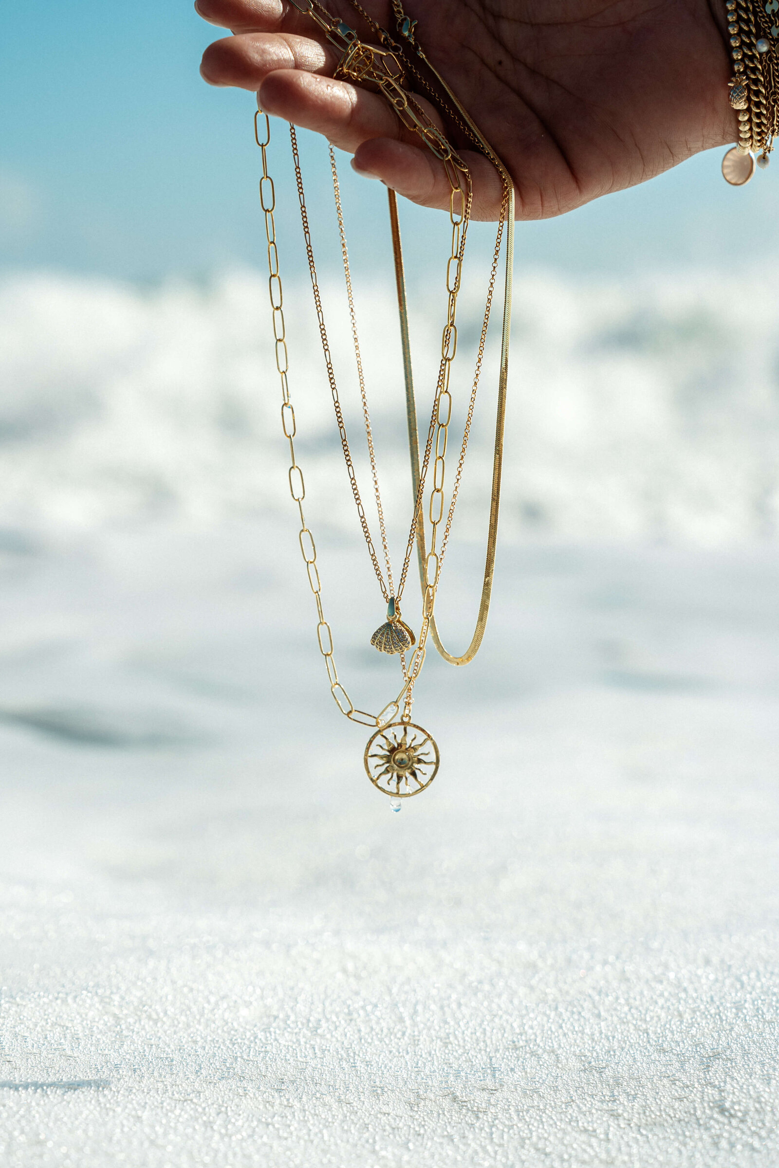 Gold jewelry with ocean in the back