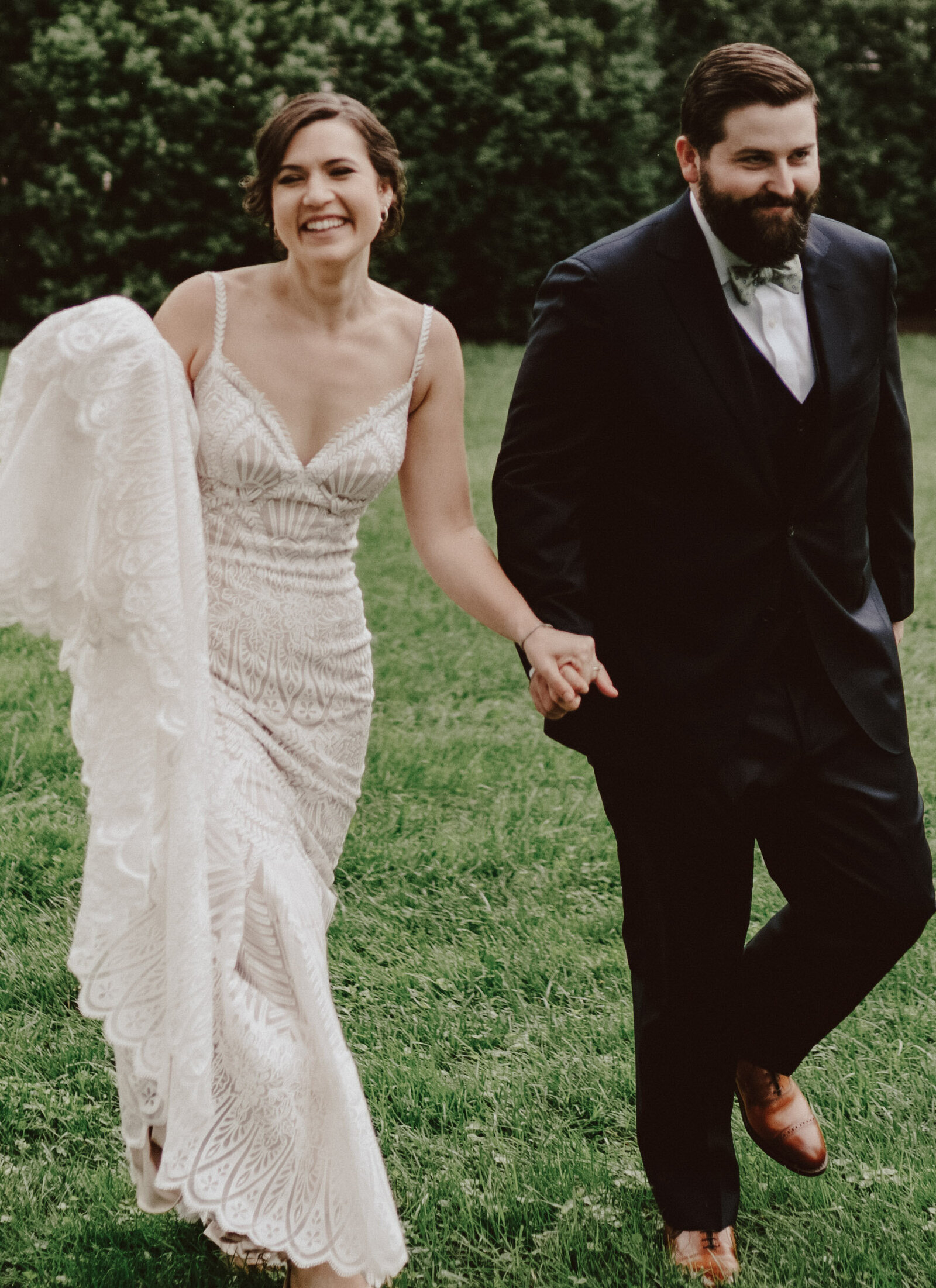 A smiling bride and groom walk through a backyard