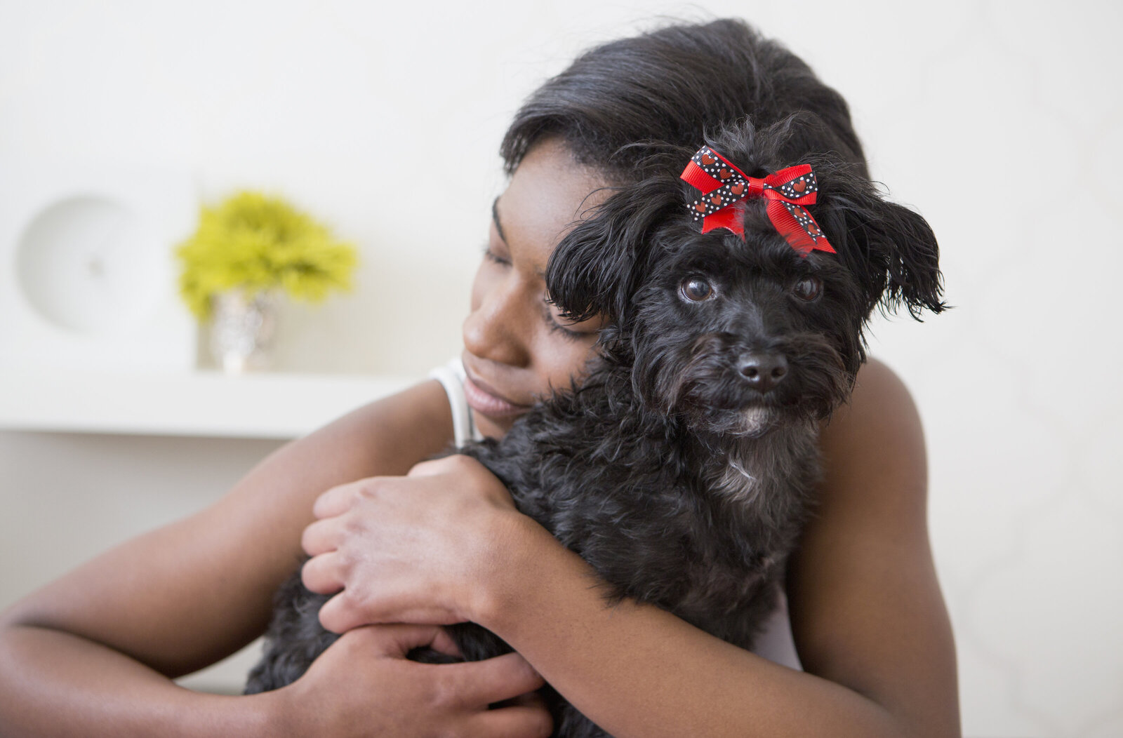 a-young-girl-hugging-her-small-black-pet-dog-B2V3LN4