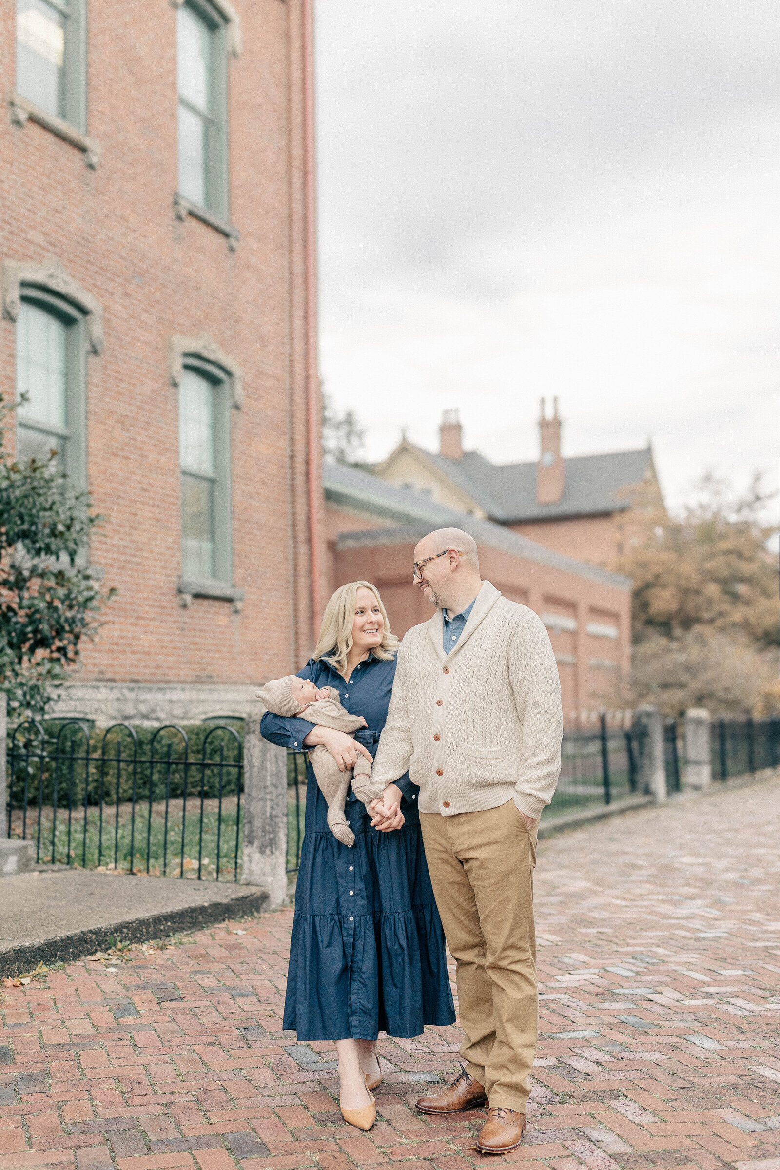 A stylish family of four strolls through a charming historic neighborhood in Kansas City during their family session with Meredith Maag, dressed in timeless neutrals and navy.